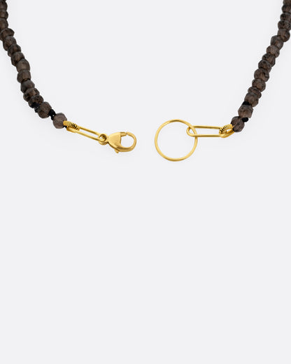 A close up of a beaded smoky quartz bracelet with a yellow gold clasp.