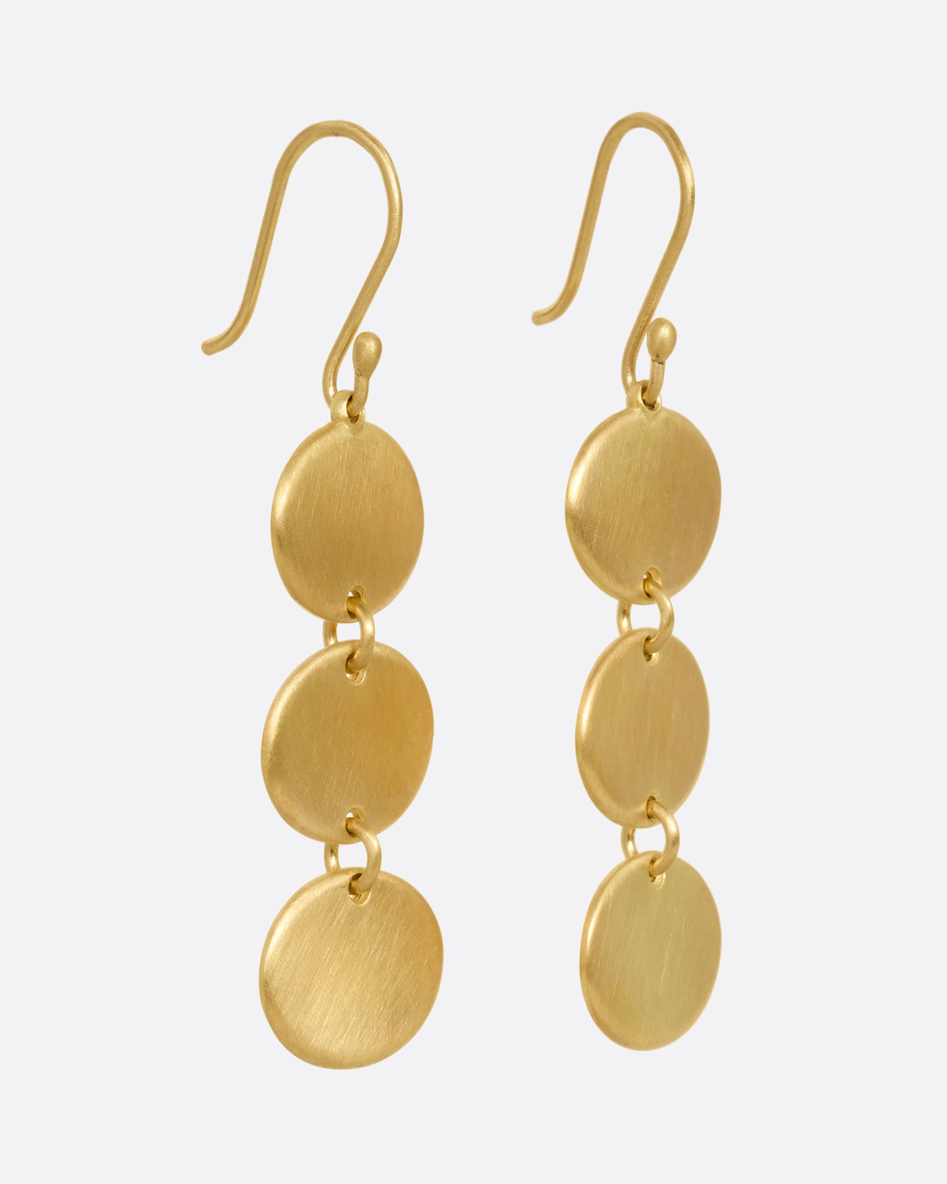 A pair of yellow gold dangle earrings with three linked ovals. Shown from the side.