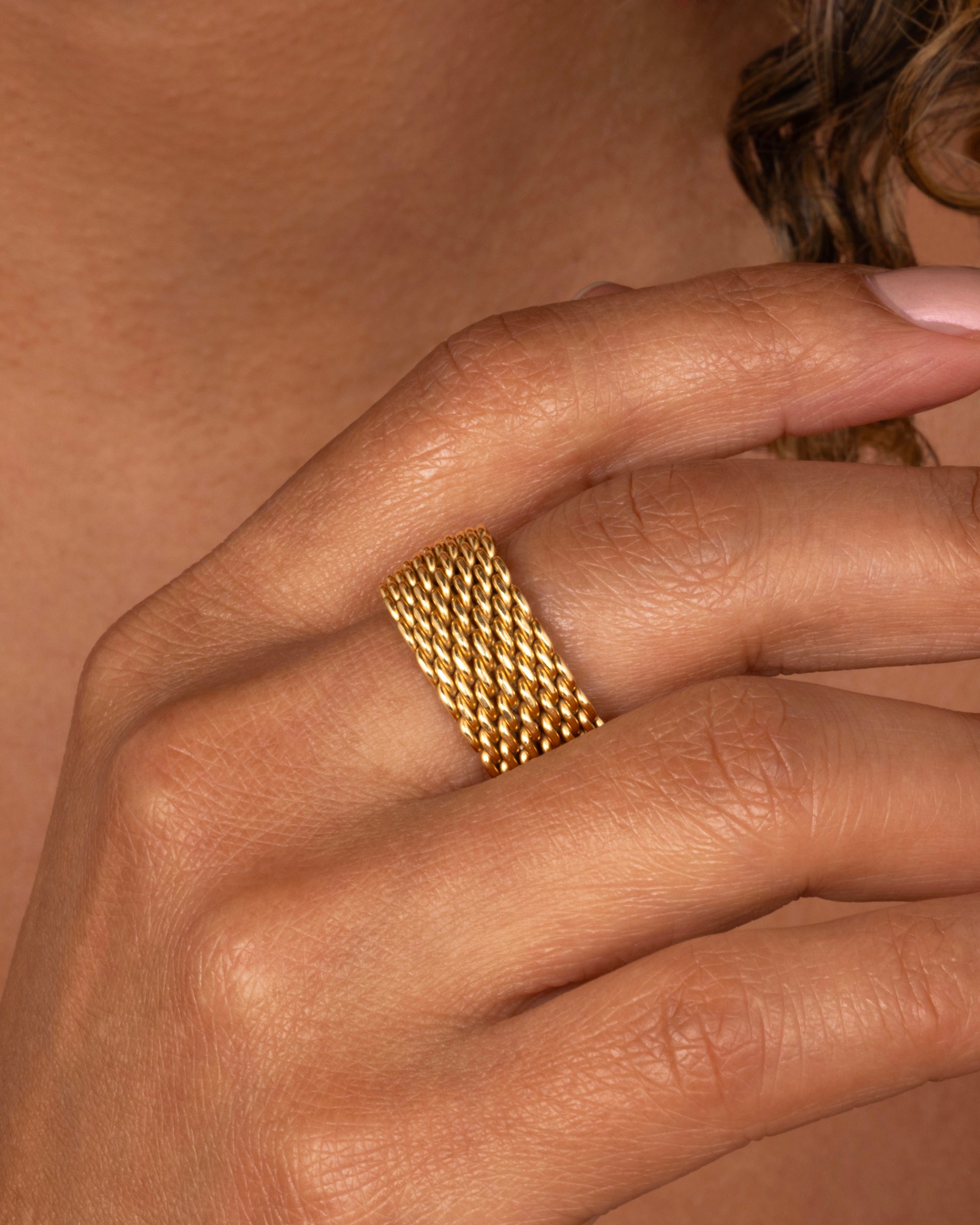 A yellow gold mesh Tiffany and Co. ring. Shown worn on a finger.