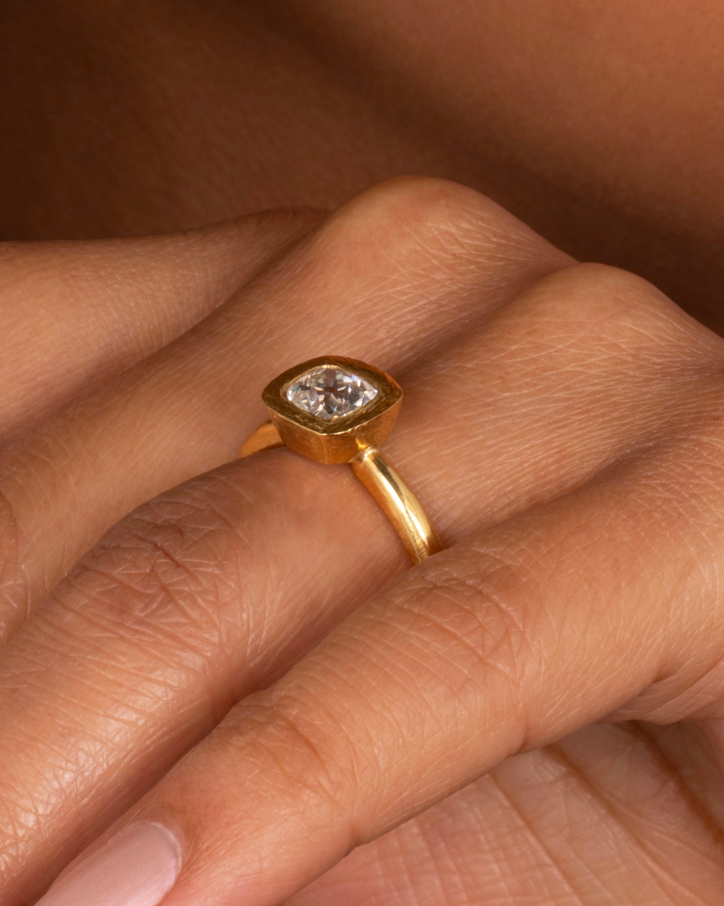 A yellow gold ring with an Old Mine Cut Diamond. Shown worn on a finger.