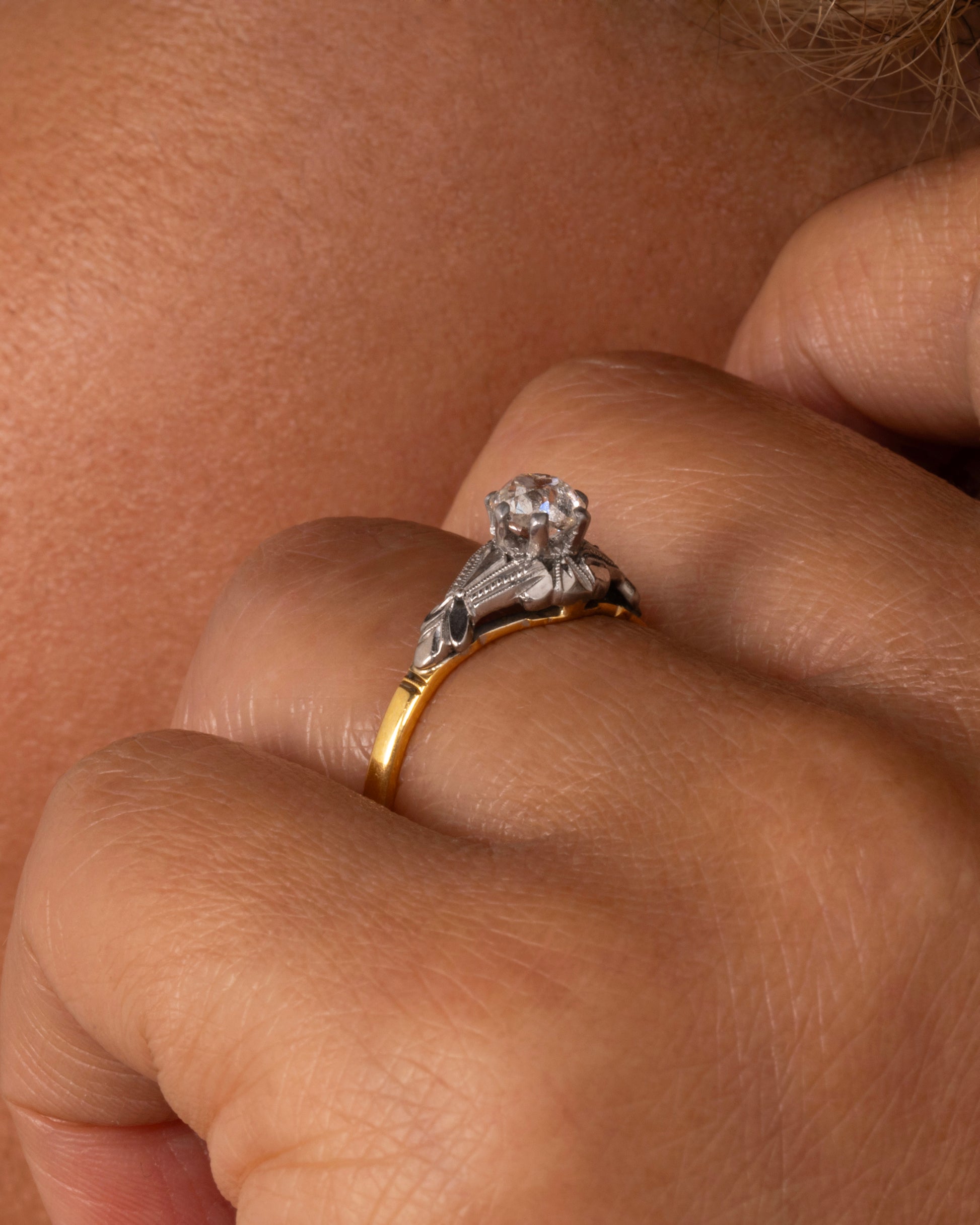 A yellow gold and platinum ring with an Old Mine Cut diamond and baguette diamonds. Shown worn on a hand.