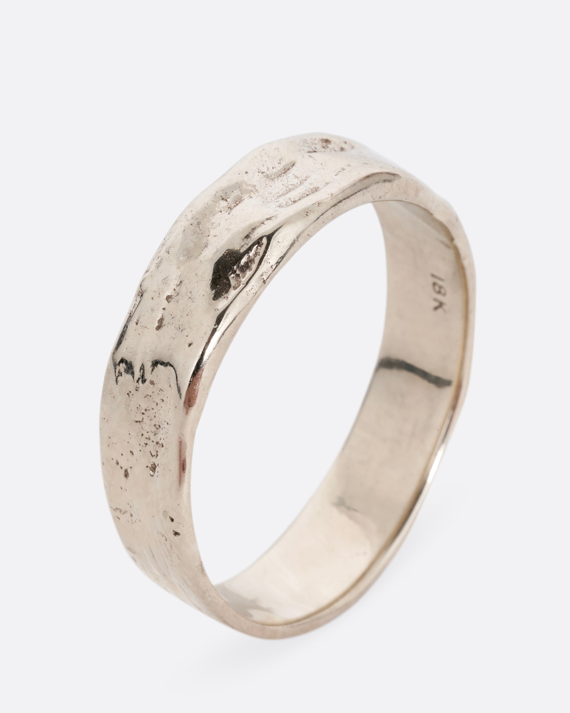 A white gold band with a textured and polished finish. Shown standing up from the side.