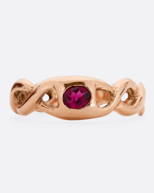 A rose gold ring with a twisted motif and pink tourmaline at the center. Shown from the front.