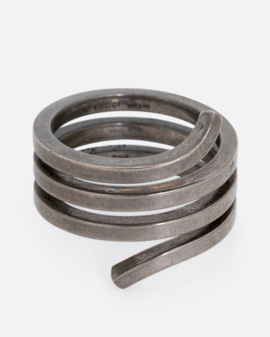A silver ring with a coil silhouette. Shown from the front. 