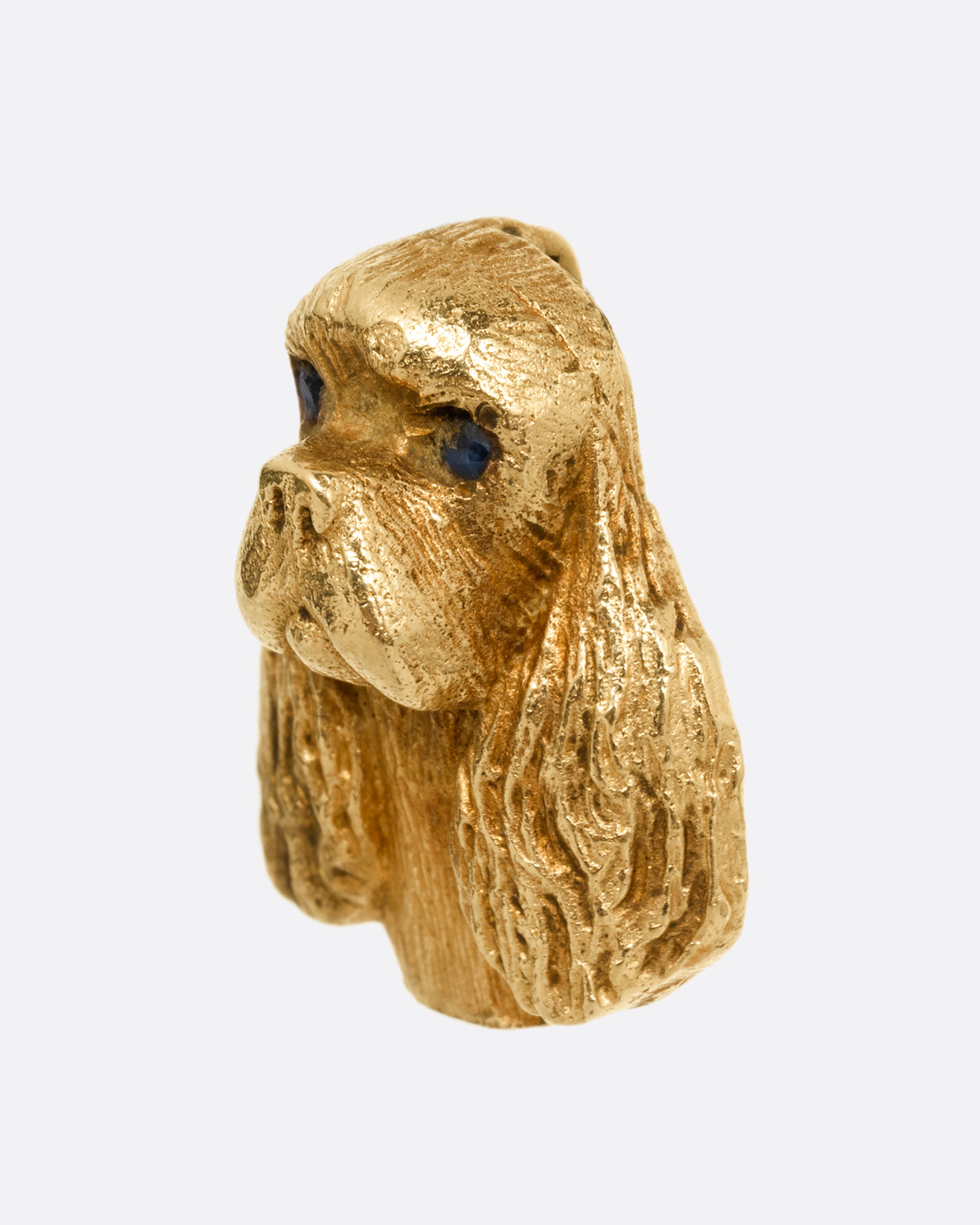 A yellow gold spaniel dog charm. Shown from the side.