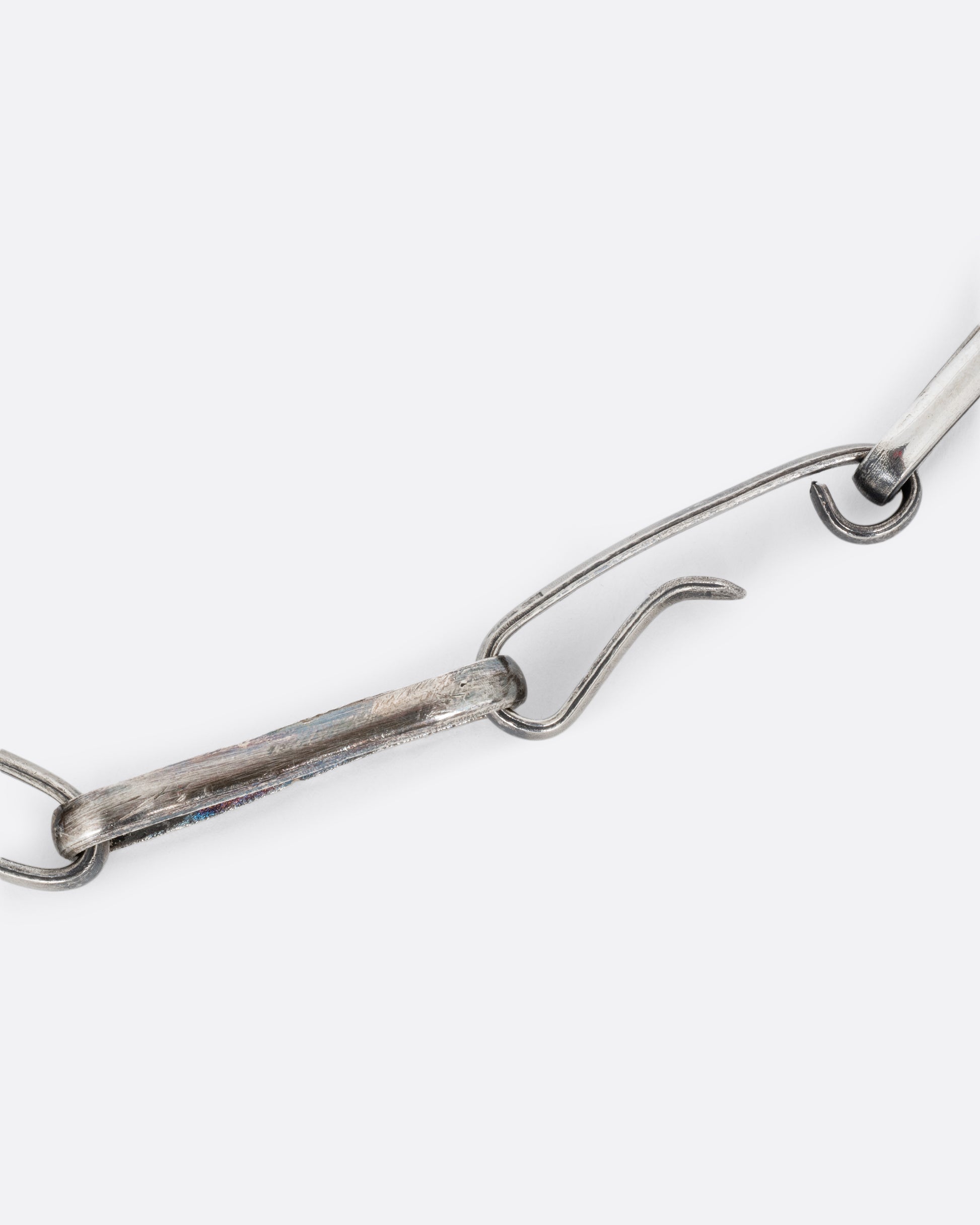 A close up of the clasp of a silver wide link cable chain necklace. Shown closed.