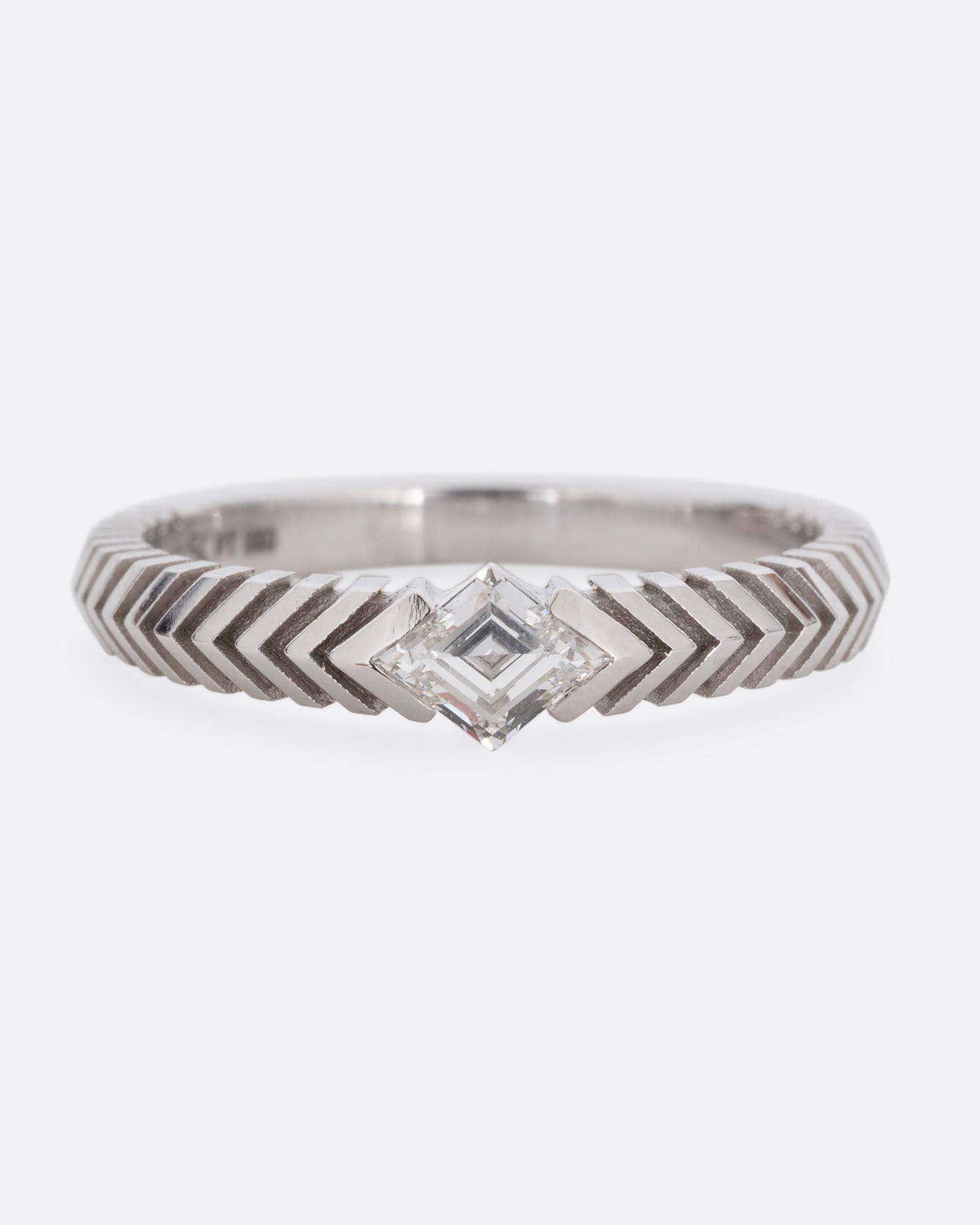 A platinum ring with a 'pleated' motif and lozenge shaped diamond at the center. Shown from the front.