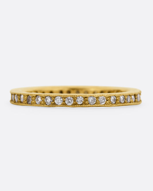 A yellow gold eternity band with bead set diamonds. Shown from the front.