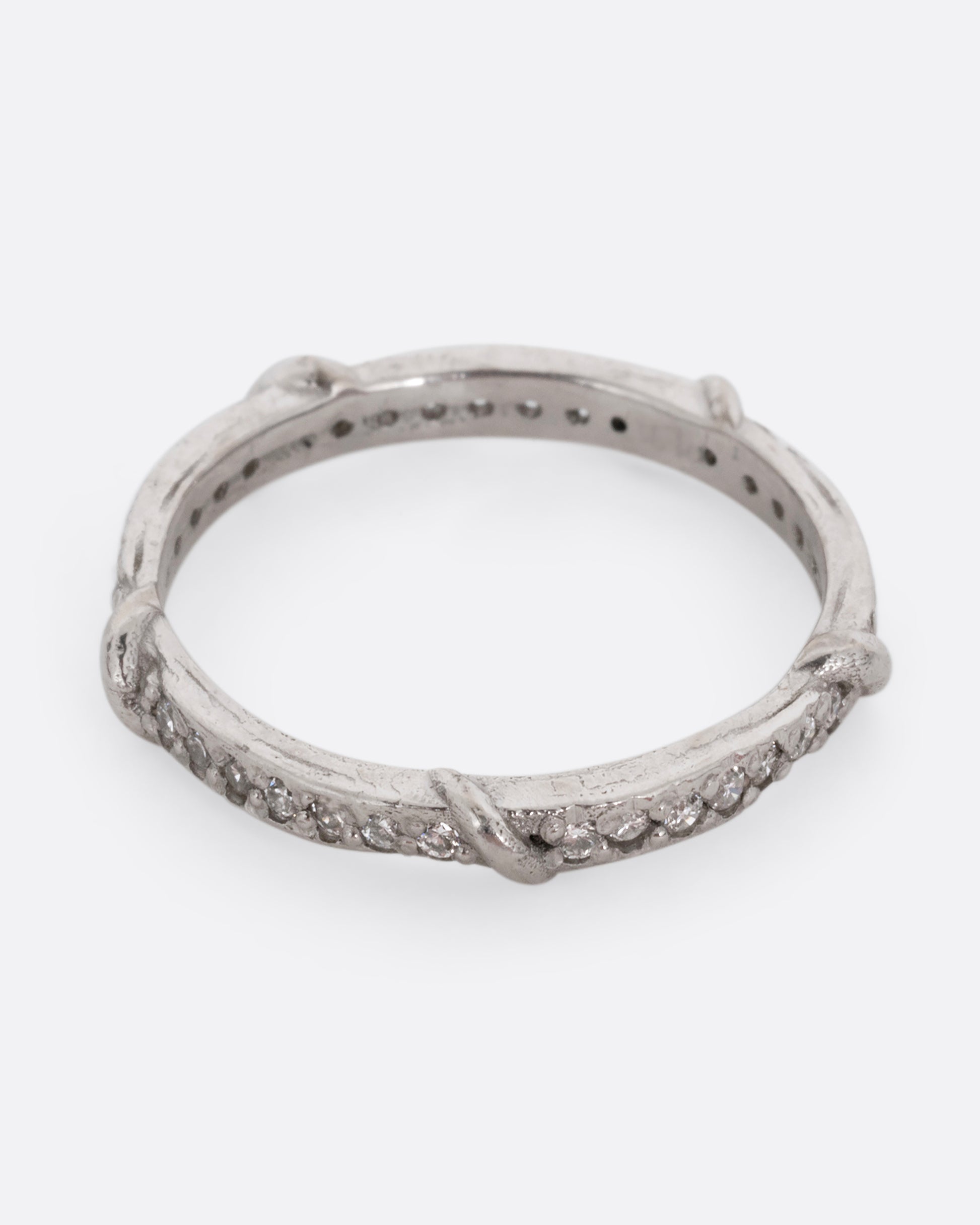 A platinum eternity band with vine detailing and brilliant white diamonds. Shown from the top.