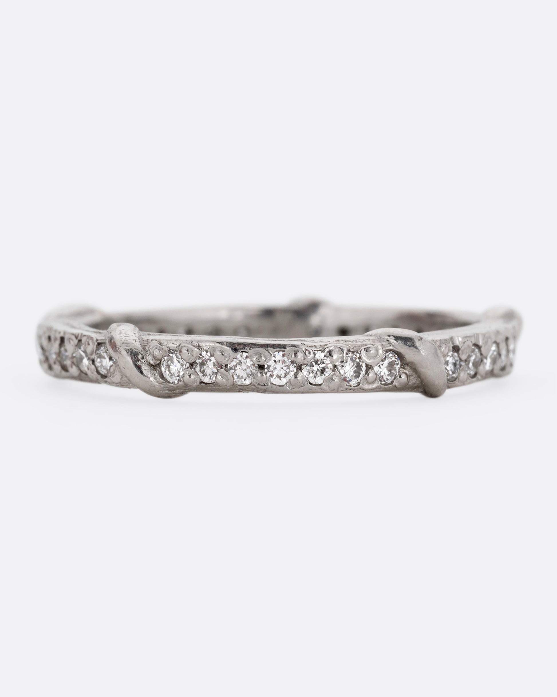 A platinum eternity band with vine detailing and brilliant white diamonds. Shown from the front.