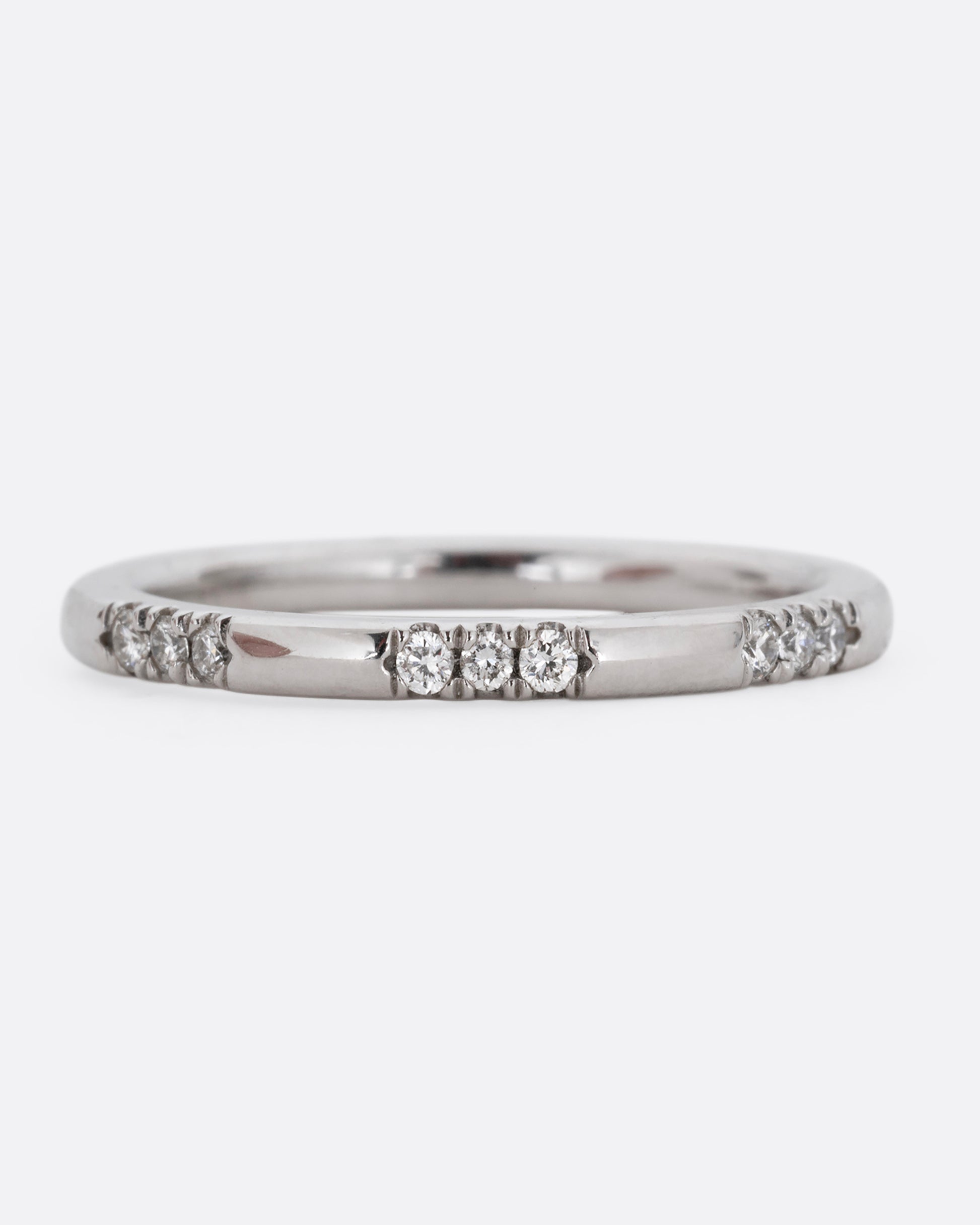 A platinum ring with stations of white diamonds. Shown from the front.