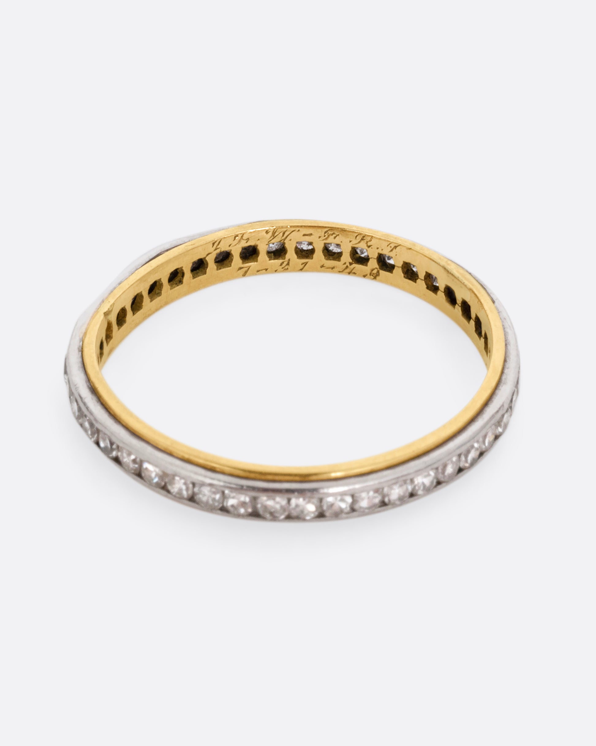 A platinum and yellow gold ring with channel set diamonds. Shown from the top.