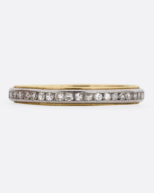 A platinum and yellow gold ring with channel set diamonds. Shown from the front.