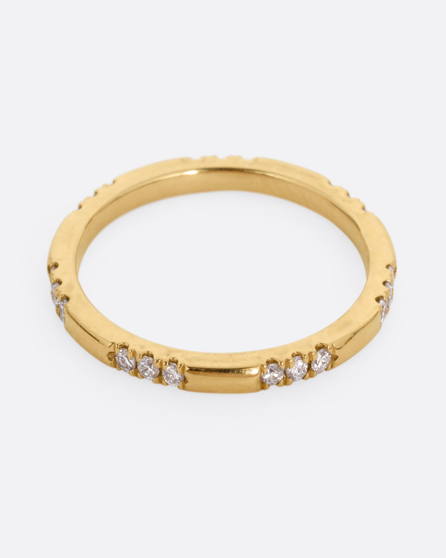 A yellow gold ring with stations of white diamonds. Shown from the front.