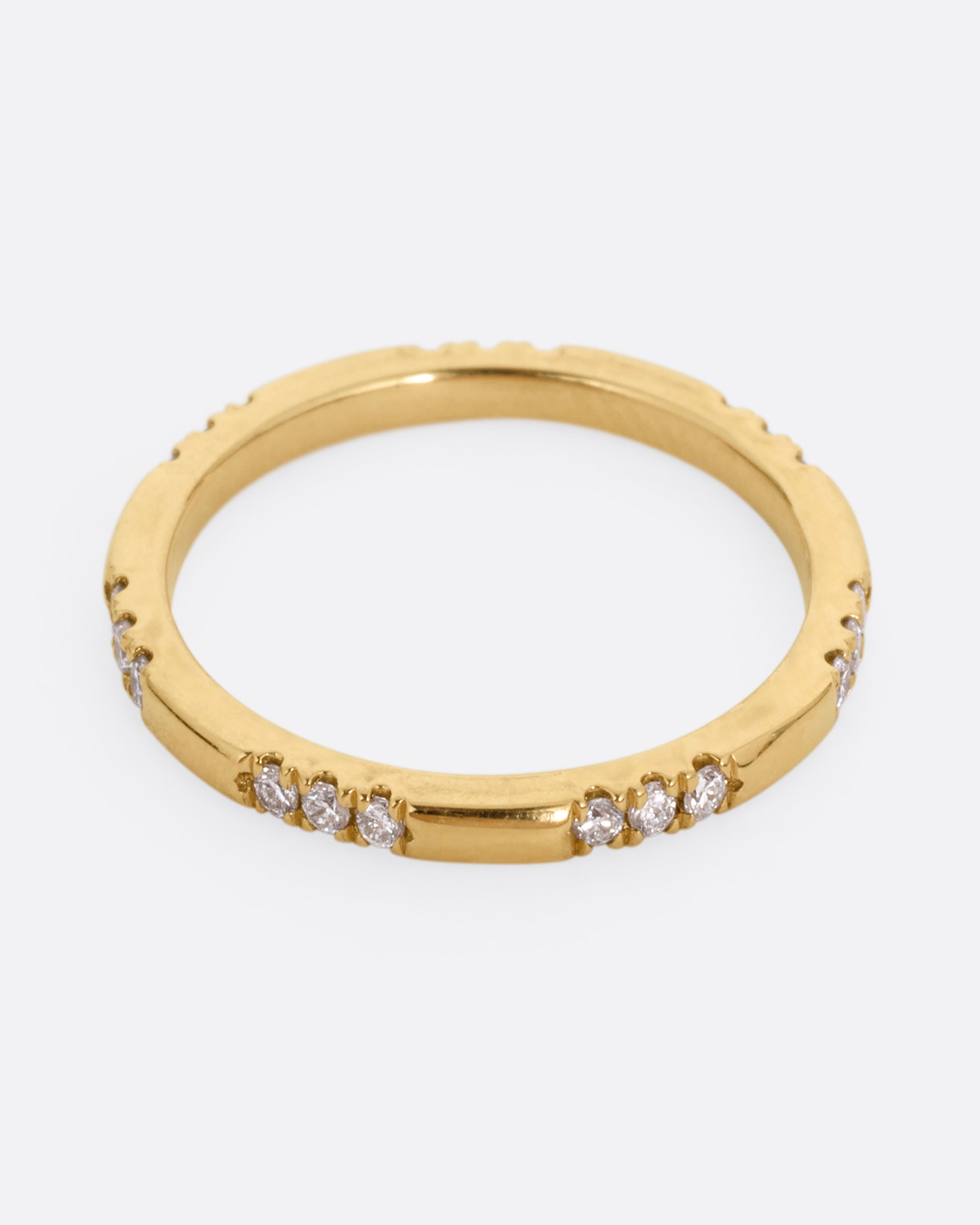 A yellow gold ring with stations of white diamonds. Shown from the front.