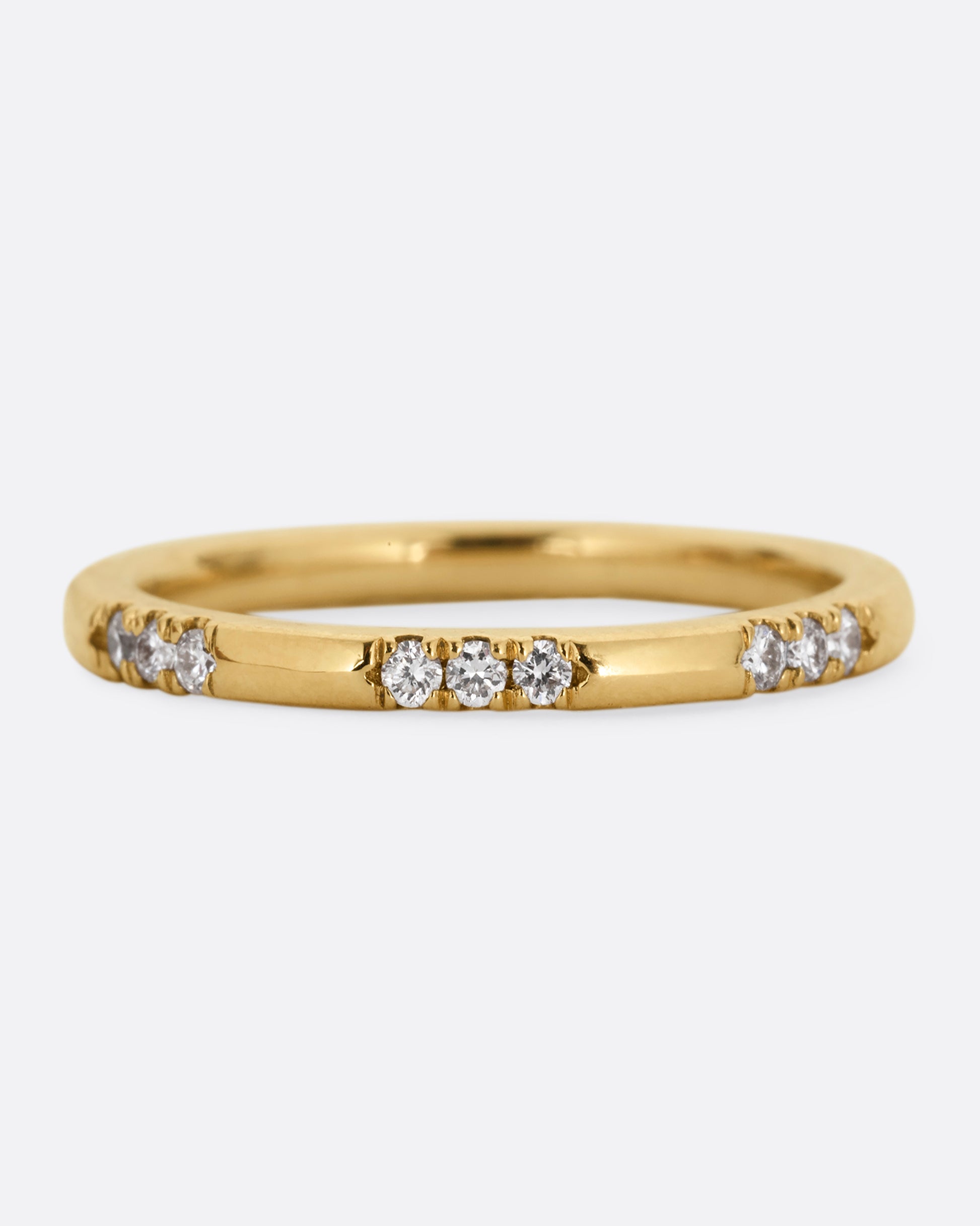 A yellow gold ring with stations of white diamonds. Shown from the front.