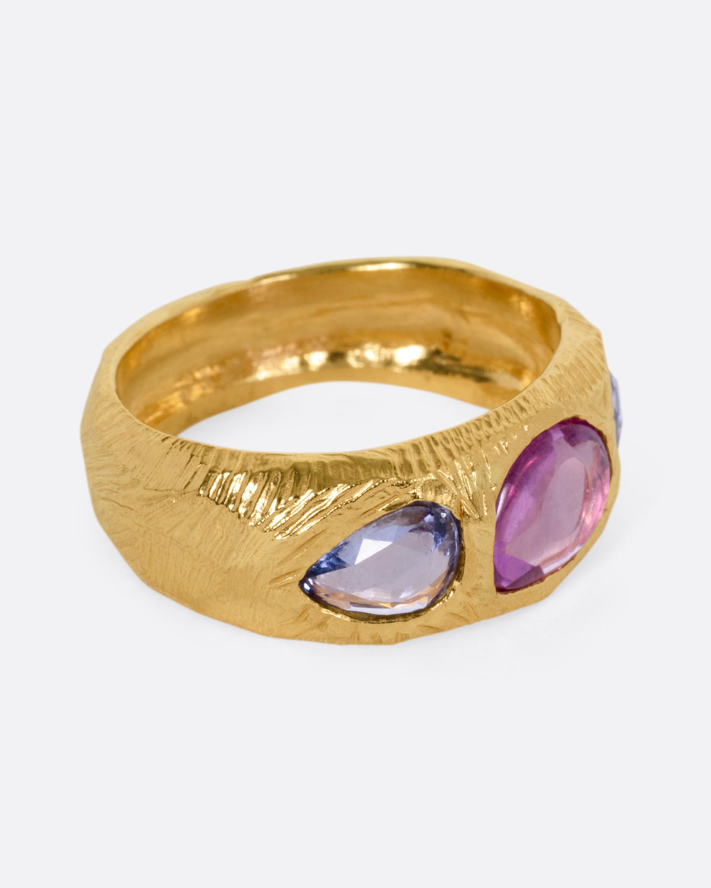 A yellow gold ring with two blue sapphires and one pink, shown from the side.