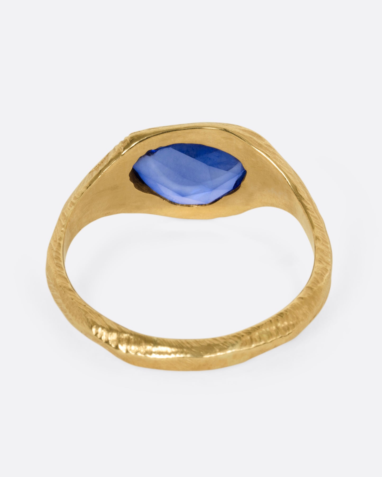A yellow gold ring with a blue sapphire, shown from the back.