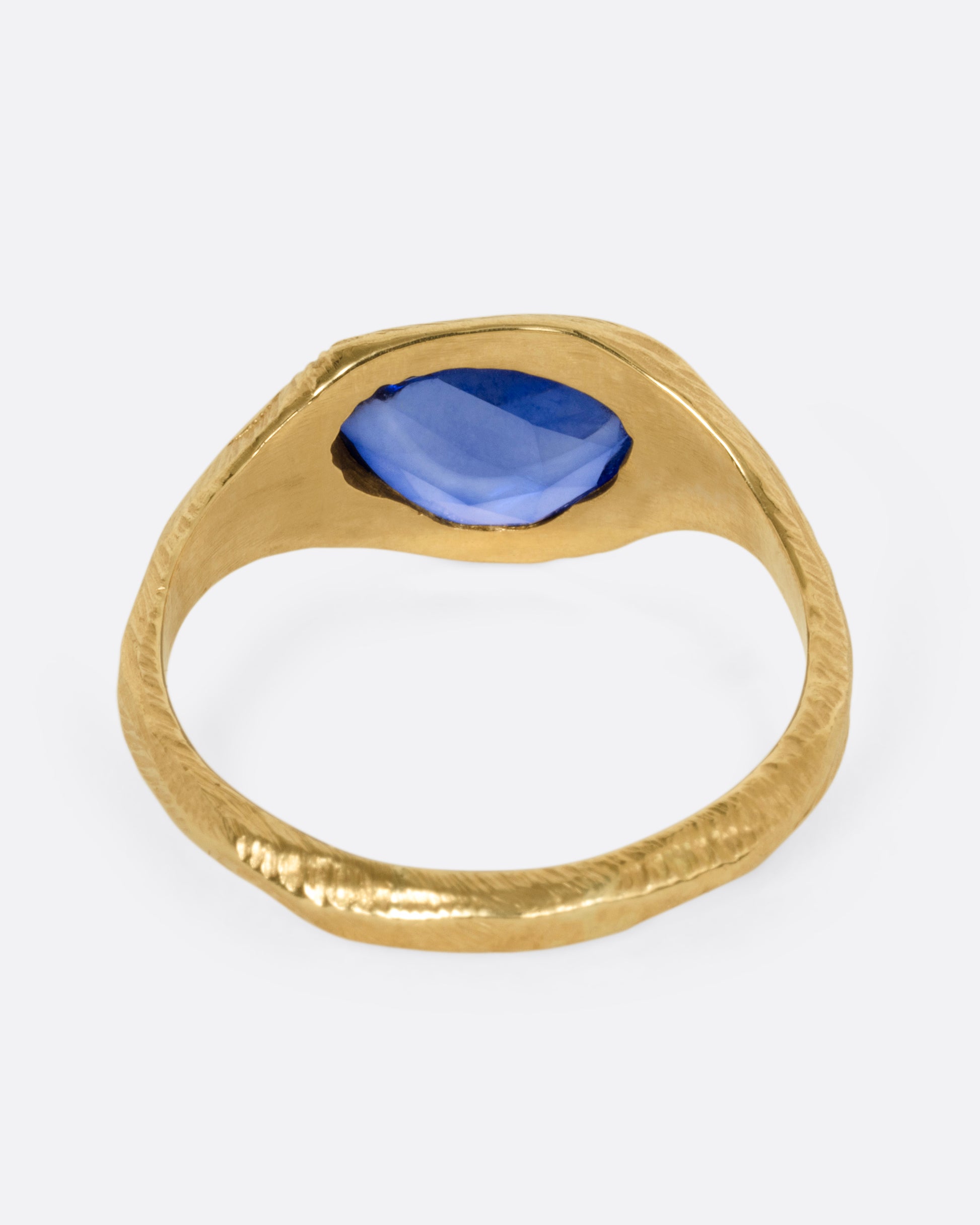 A yellow gold ring with a blue sapphire, shown from the back.