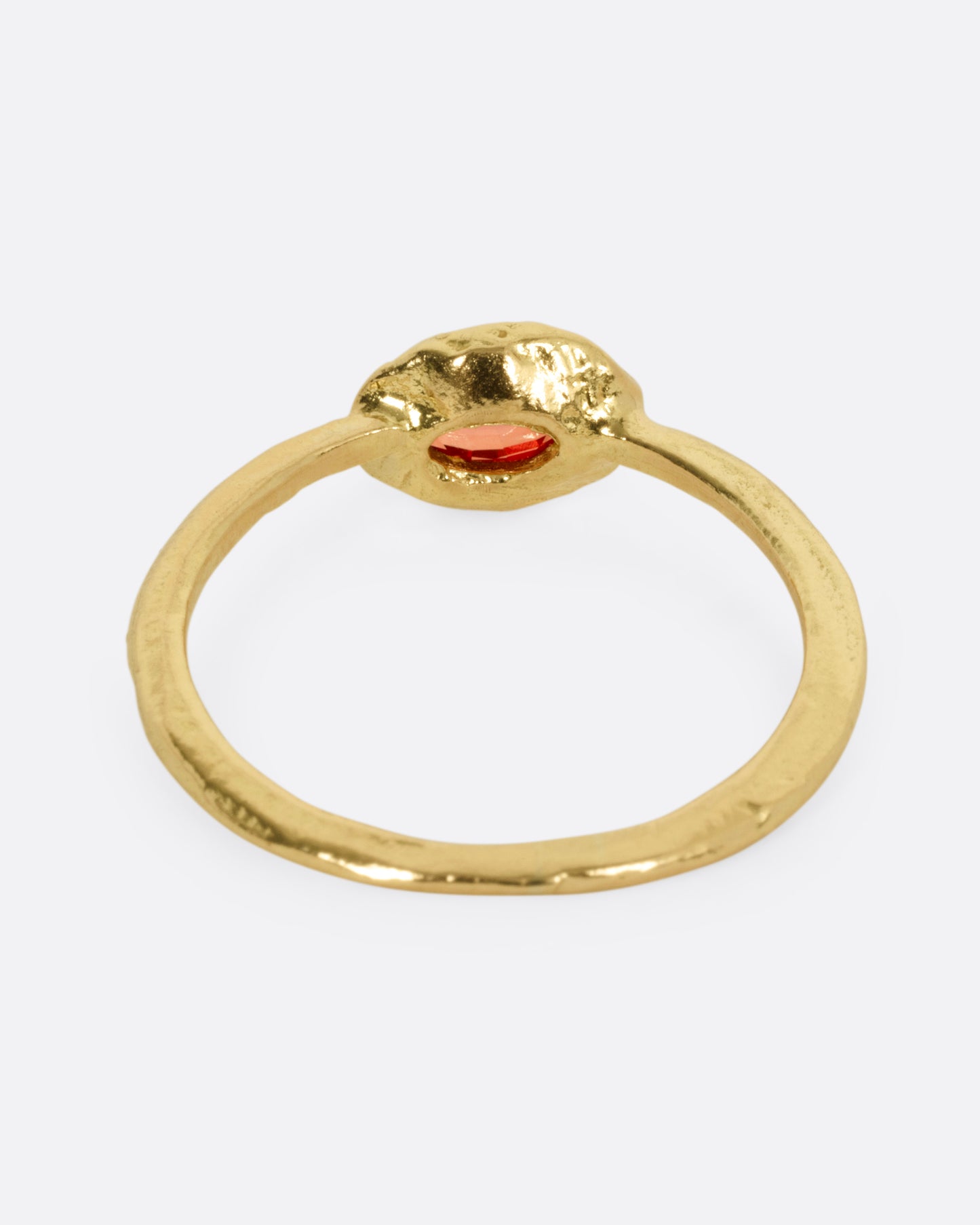 A yellow gold ring with a red sapphire, shown from the back.