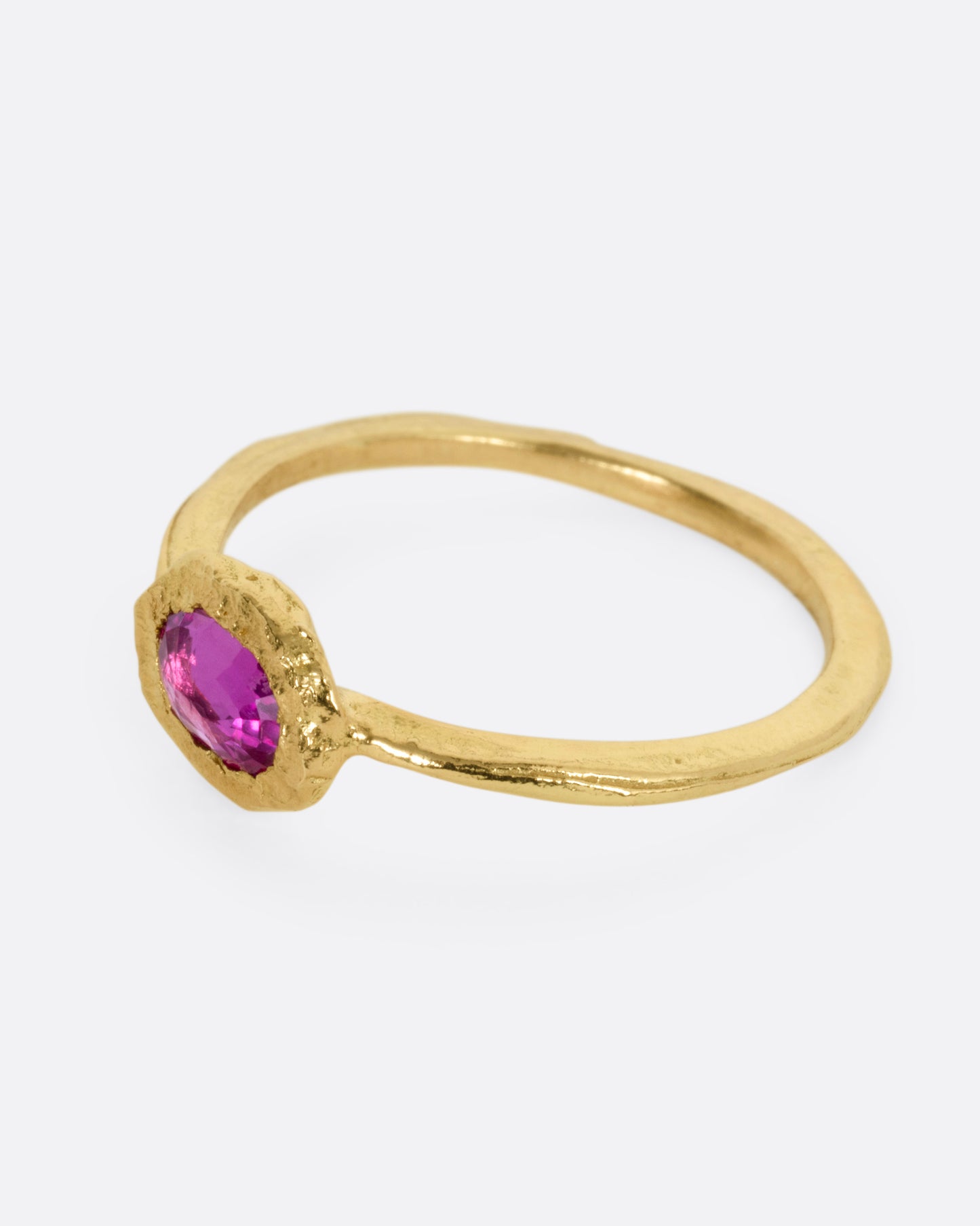 A yellow gold ring with an oval ruby, shown from the side.