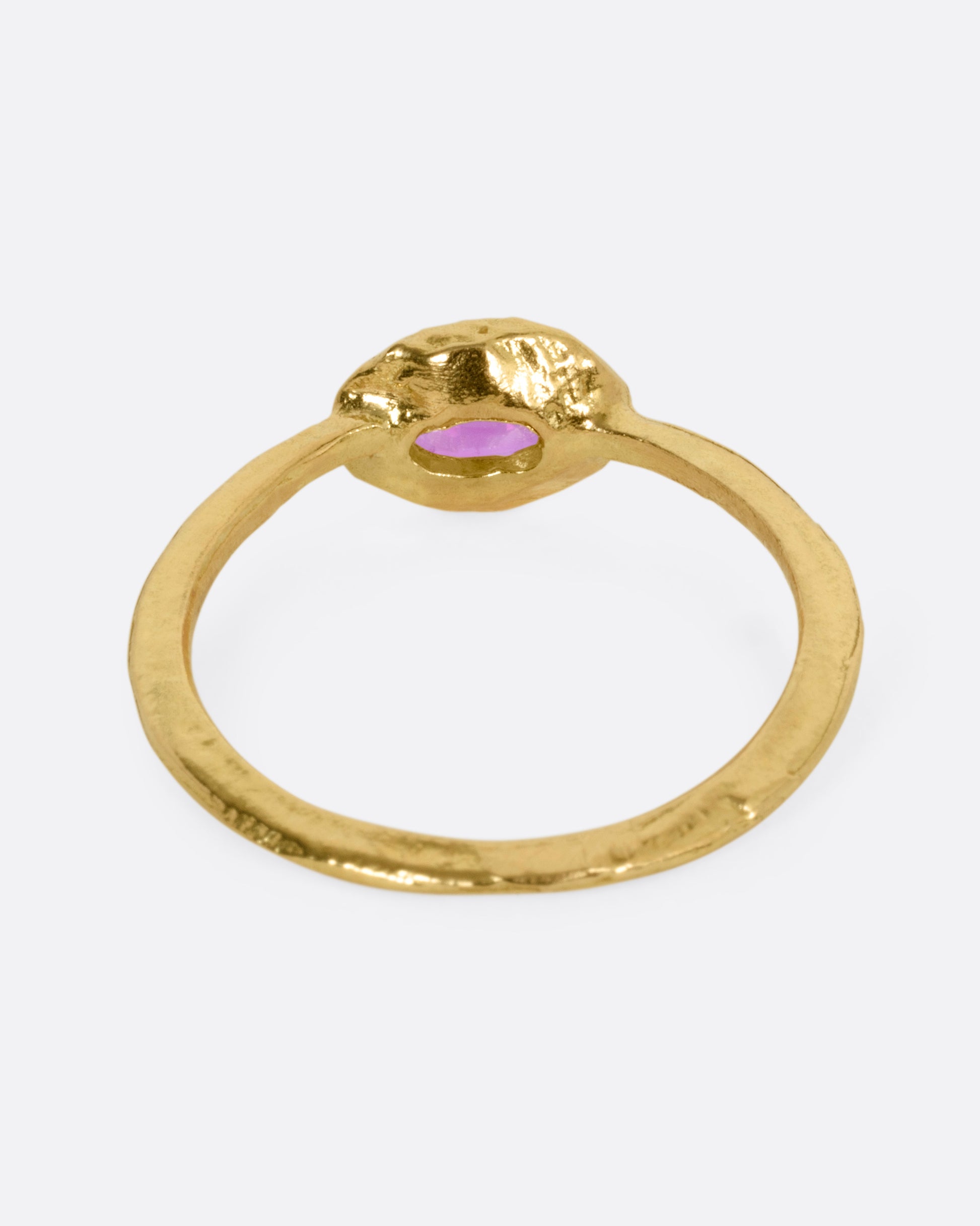 A yellow gold ring with an oval ruby, shown from the back.