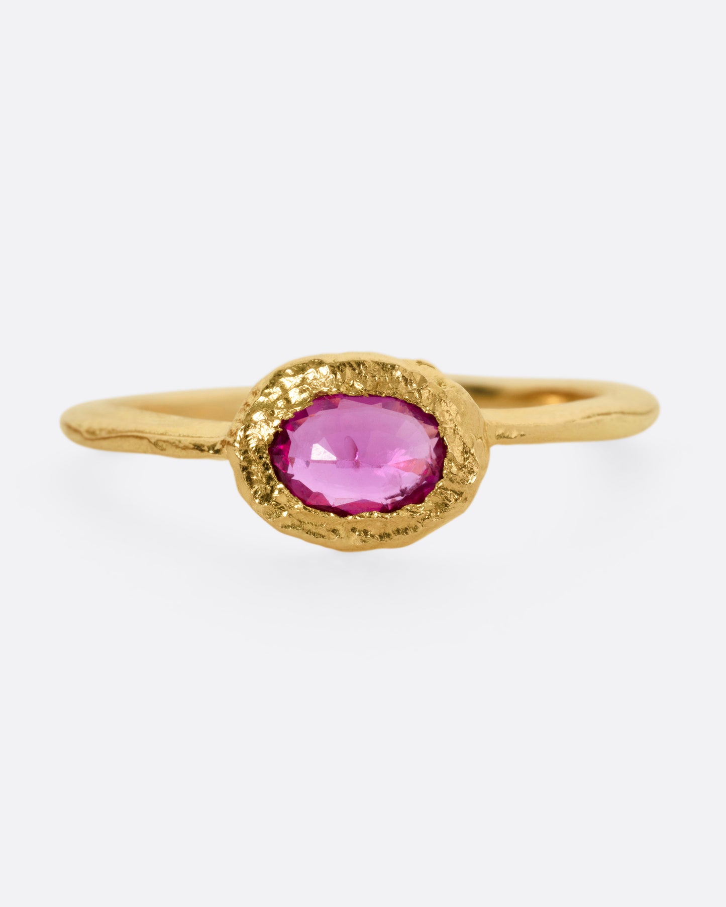 A yellow gold ring with an oval ruby, shown from the front.