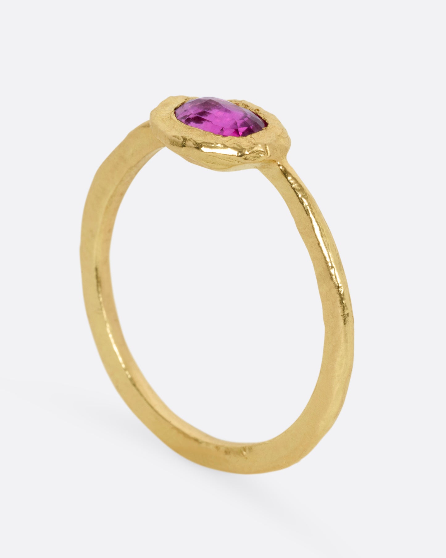 A yellow gold ring with an oval ruby, shown from the side standing up.