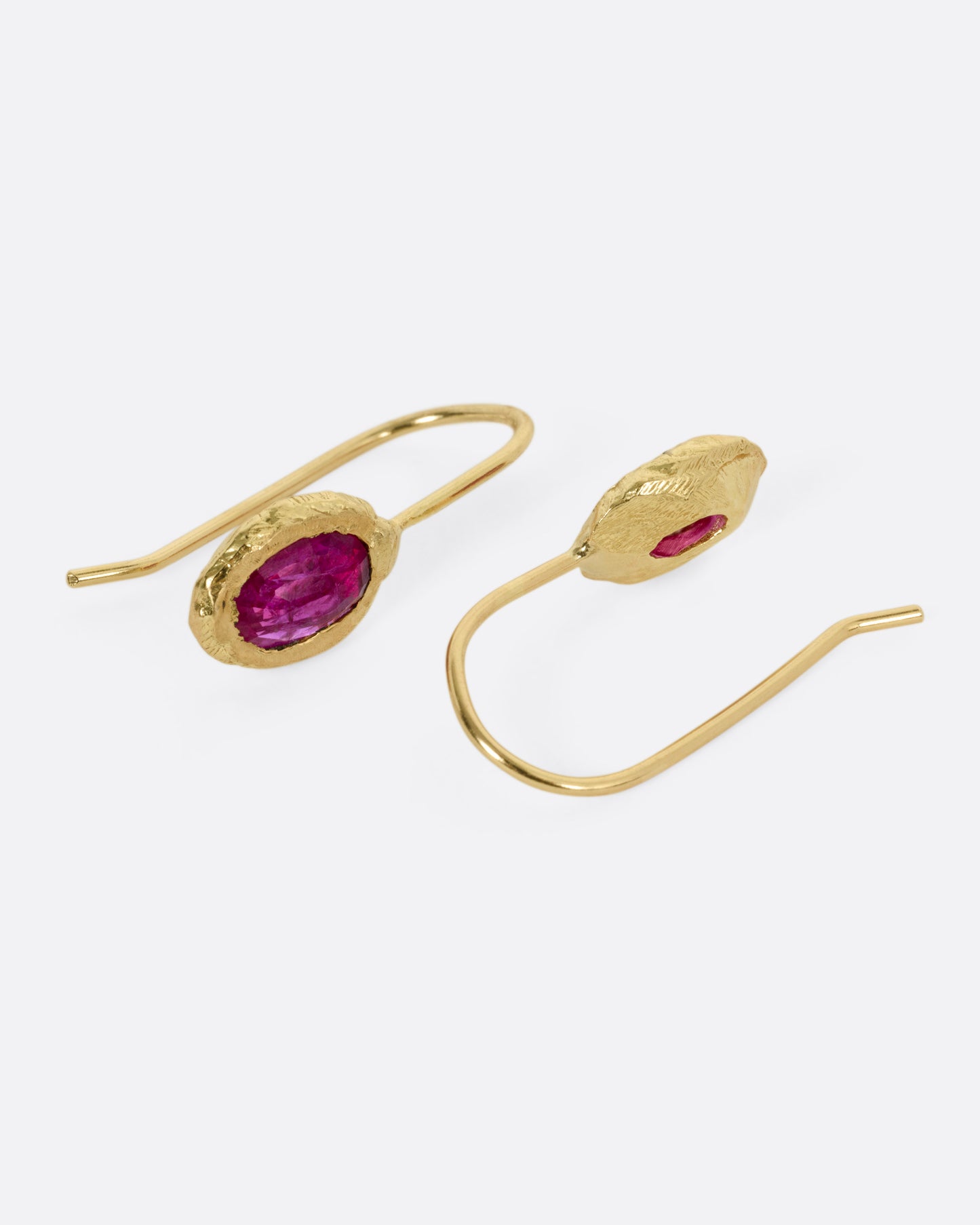 A pair of yellow gold earrings with rubies, shown from the side.