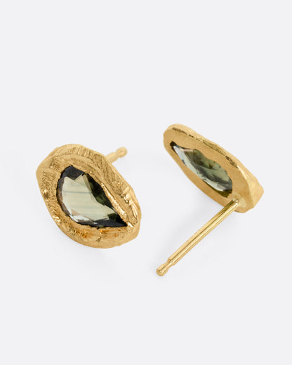 Yellow gold green sapphire stud earrings, the pair laid flat showing the posts