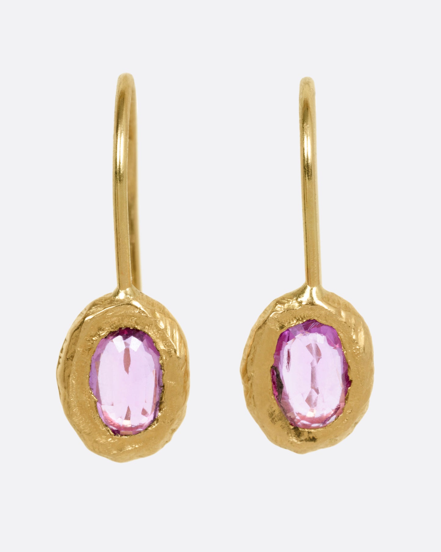 A pair of yellow gold earrings with pink sapphires, shown from the front.