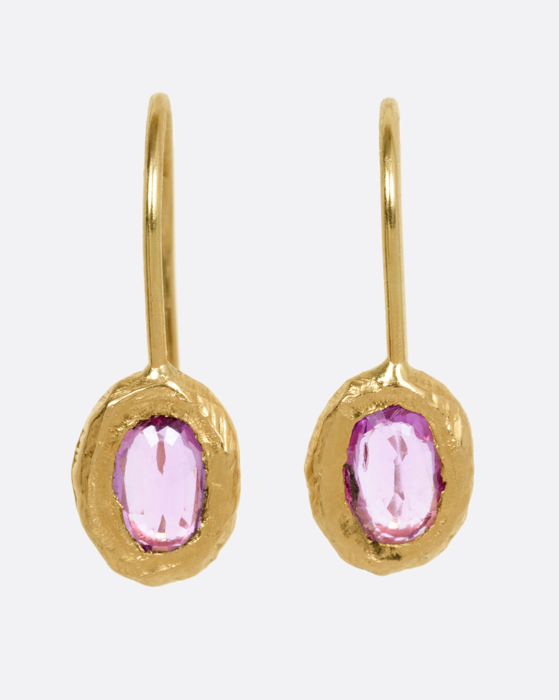 A pair of yellow gold earrings with pink sapphires, shown from the front.