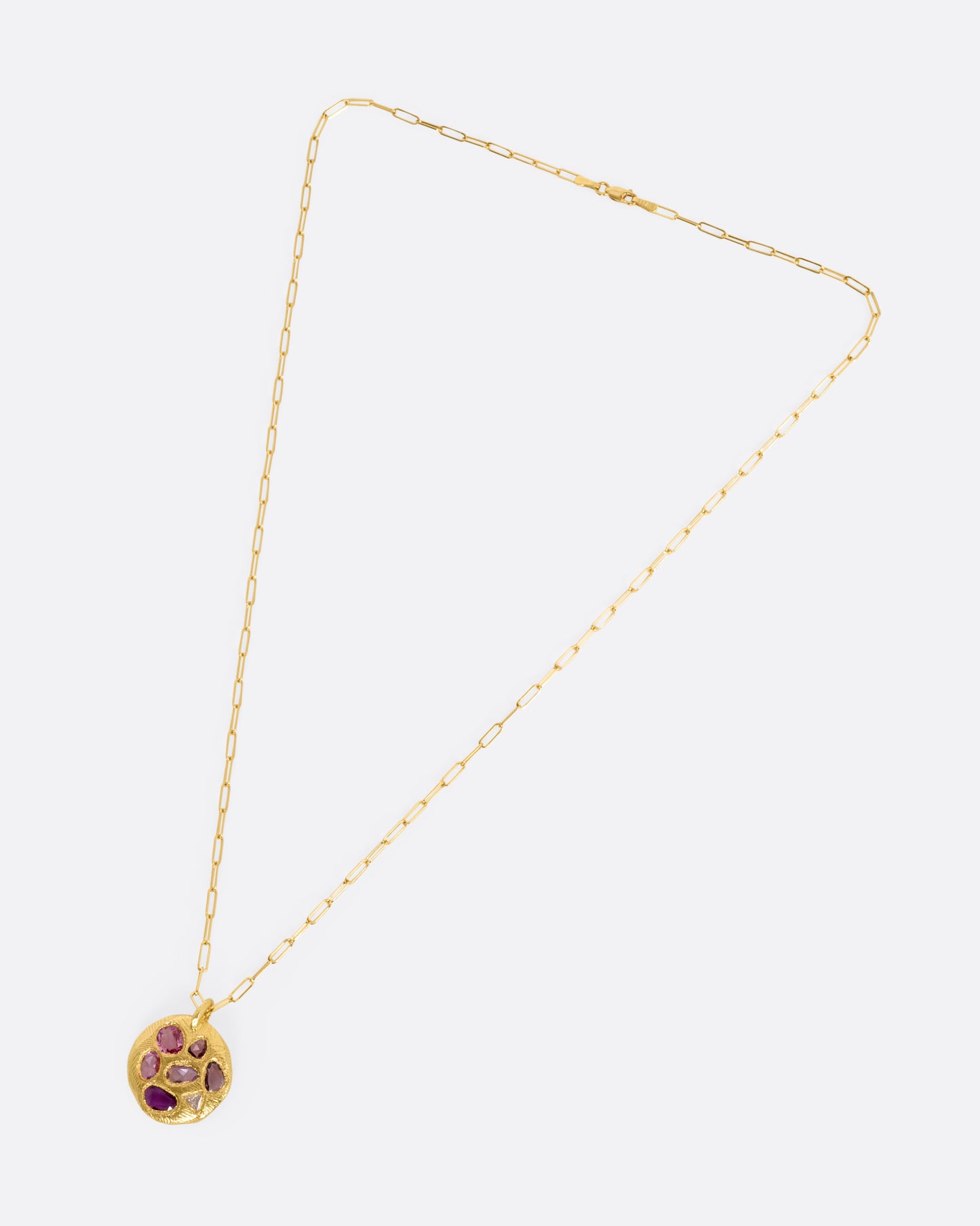 A yellow gold necklace with a circular pendant with pink sapphires and one trillion cut diamond, shown from the front.
