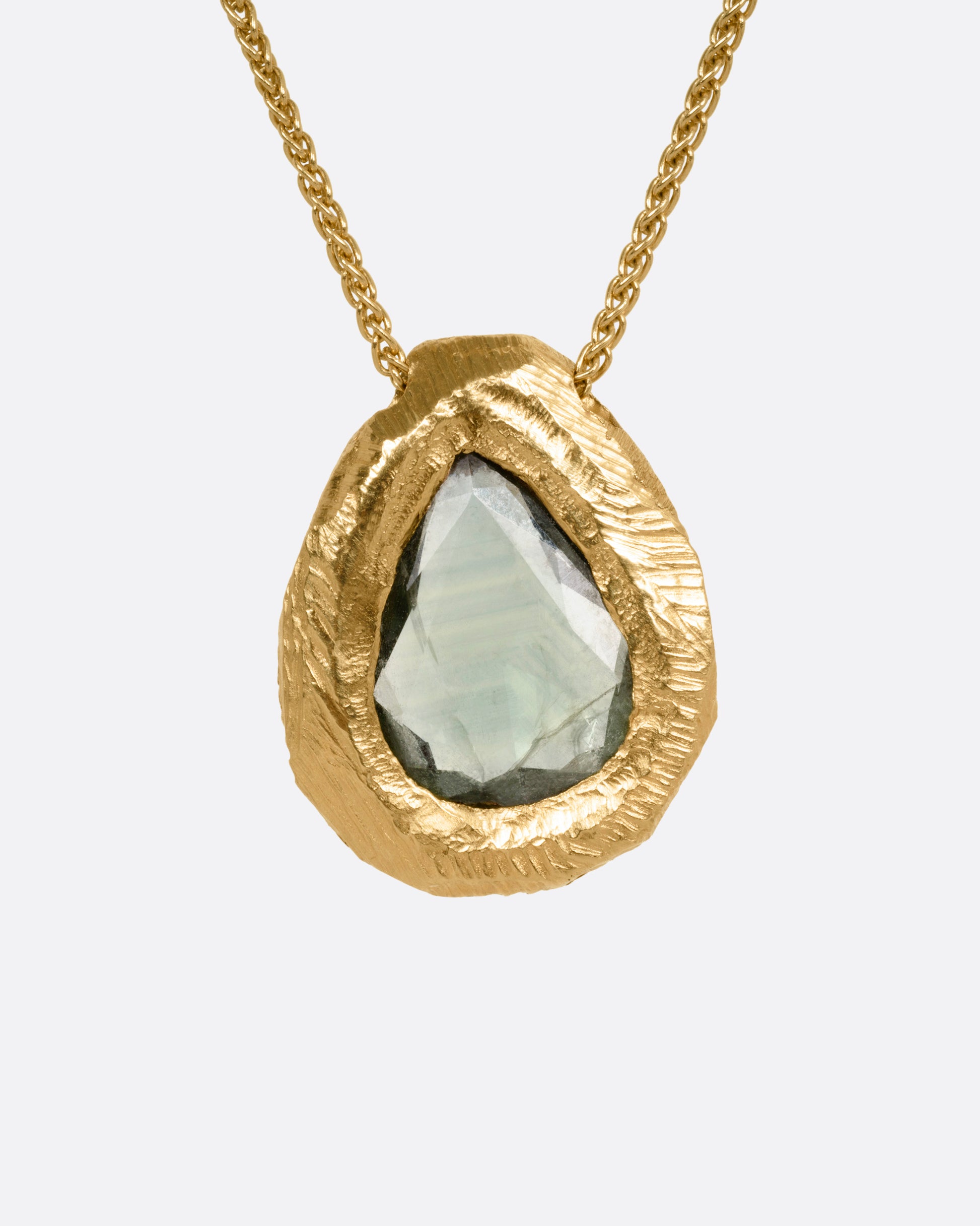 A yellow gold necklace with a green rose cut sapphire pendant, shown from the front.