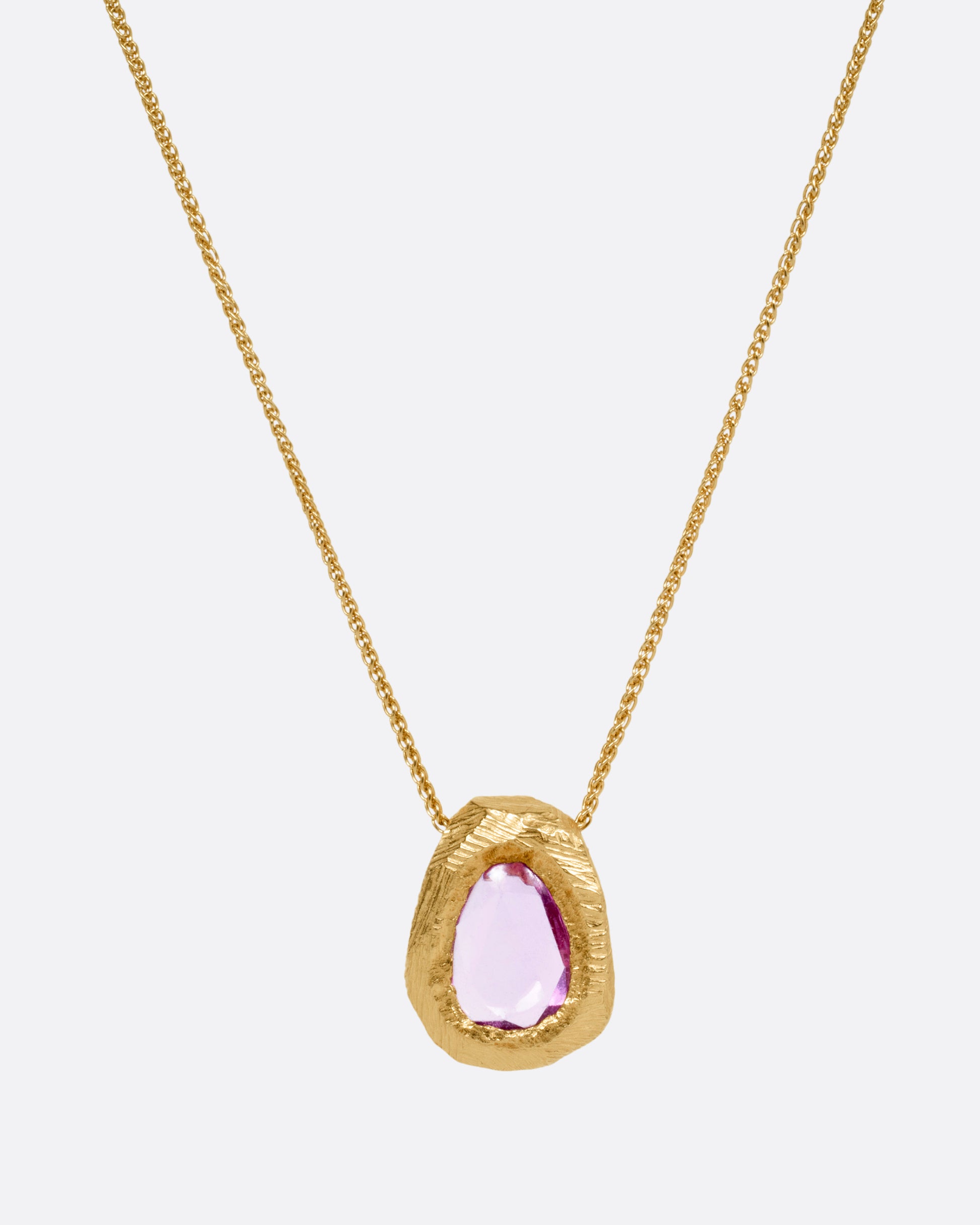 A yellow gold necklace with a pink sapphire pendant, shown from the front.