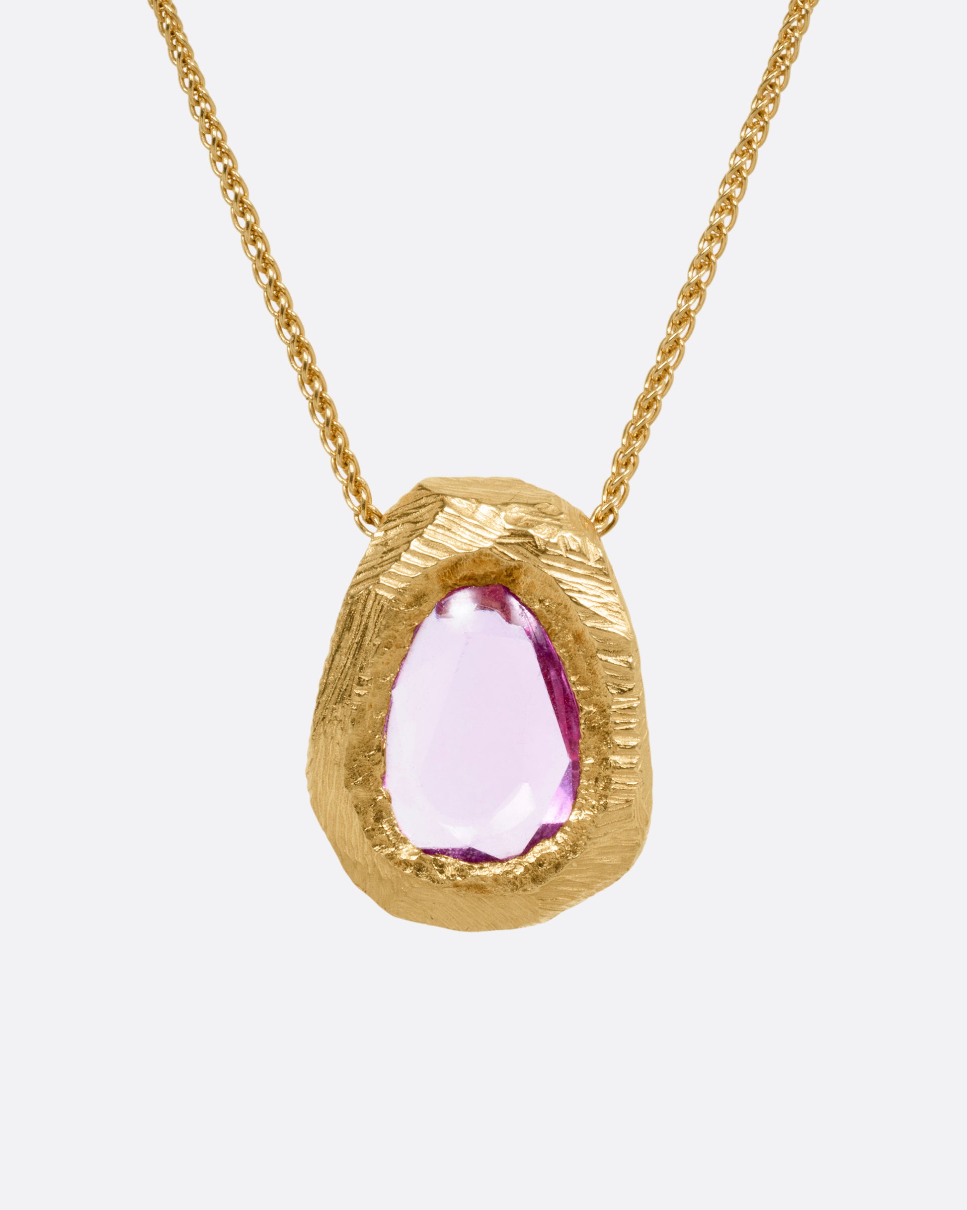 A yellow gold necklace with a pink sapphire pendant, shown from the front.