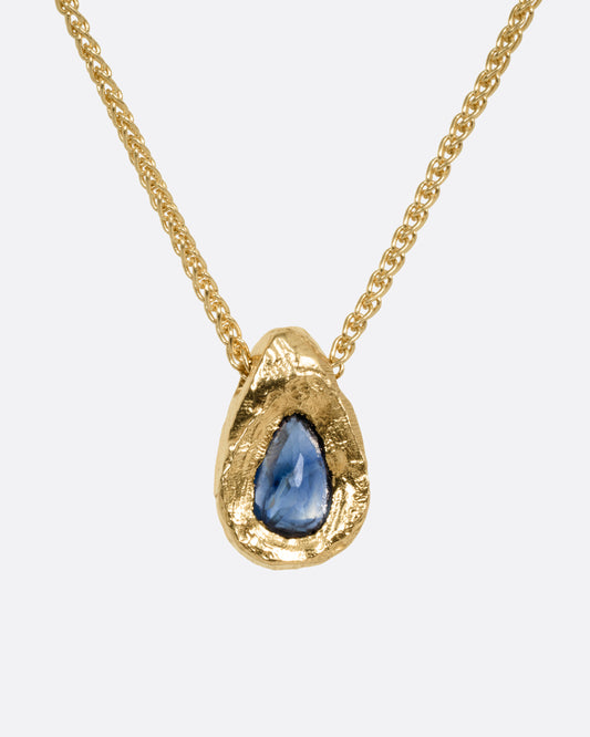 A yellow gold necklace with a blue sapphire pendant shown from the front.