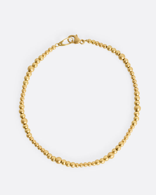 A yellow gold bracelet with graduated beads, shown from the top.