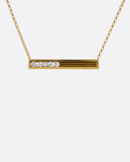 Januka necklace in 18k yellow gold, a flat gold bar with five round diamonds that slide inside a channel