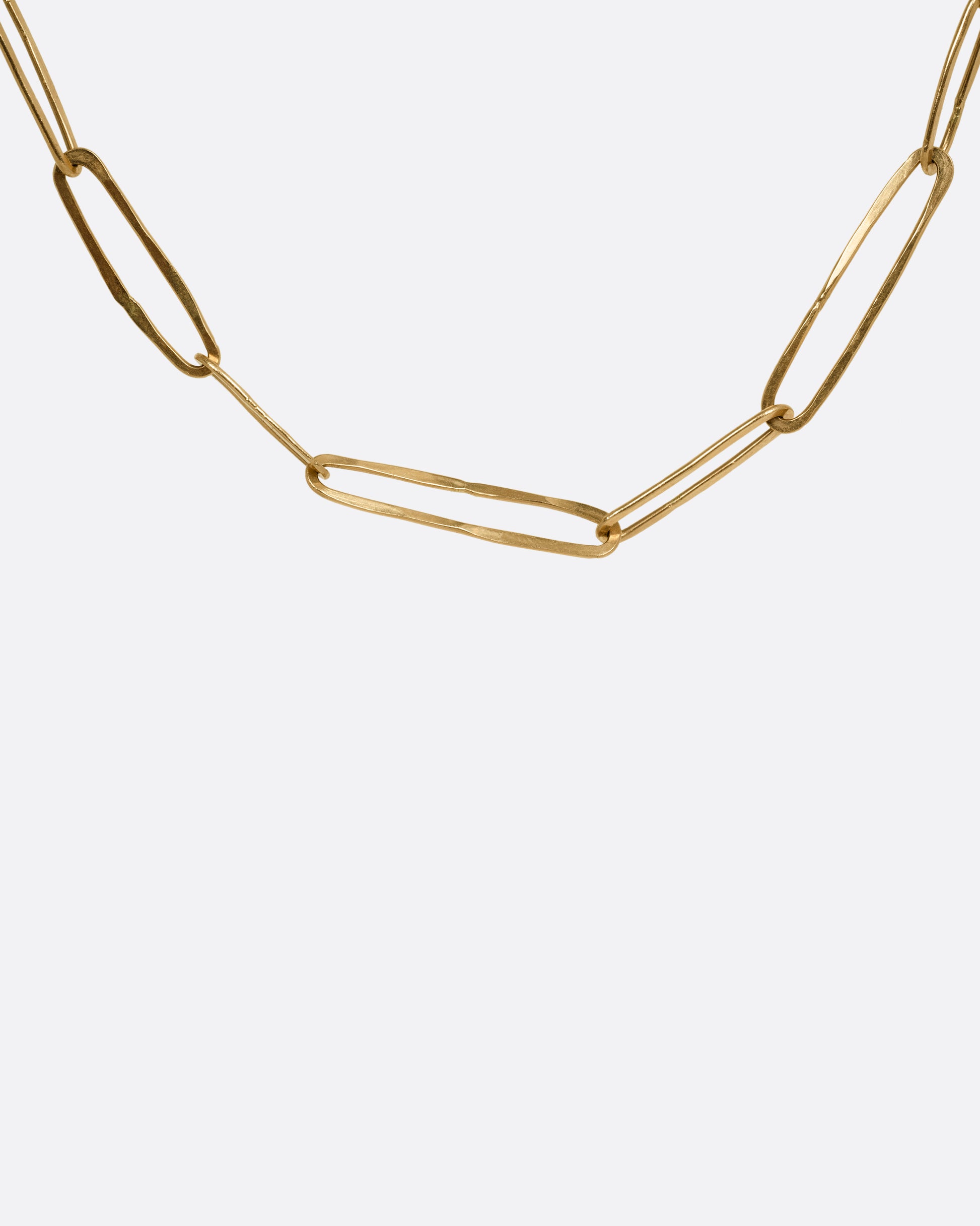 A close up of a yellow gold paperclip chain shown from the front.