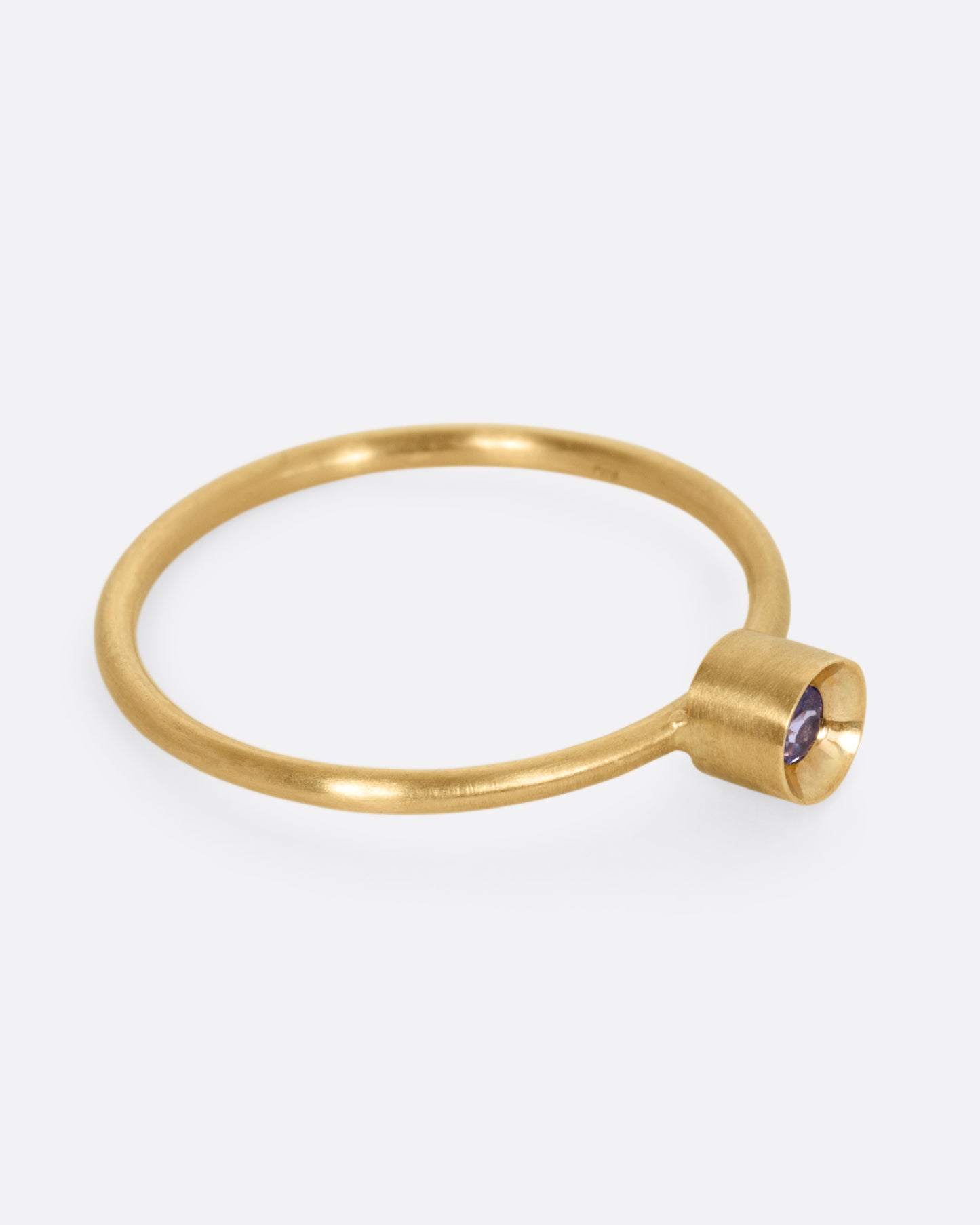 A yellow gold ring with a tanzanite in a raised bezel, shown from the side.