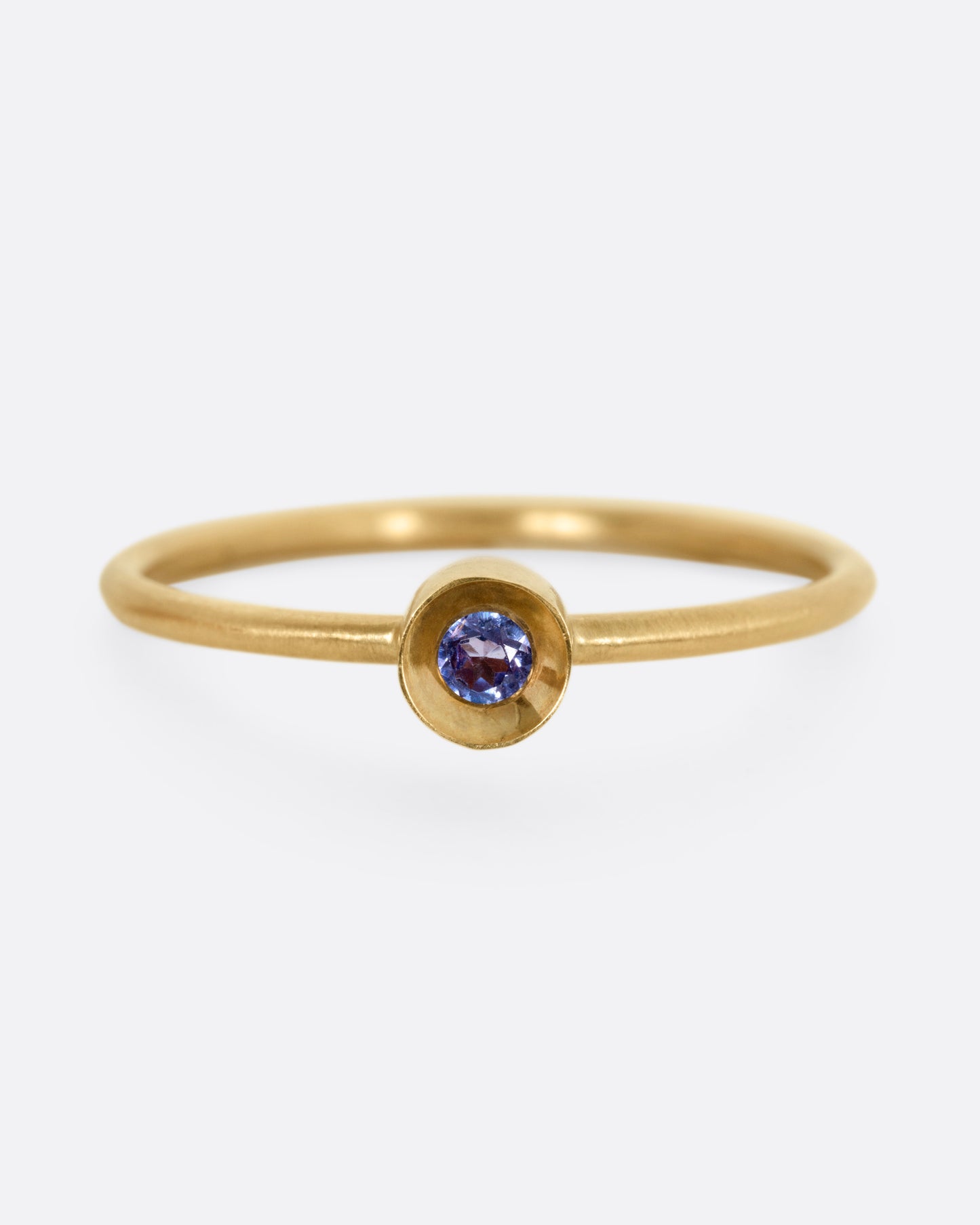 A yellow gold ring with a tanzanite in a raised bezel, shown from the front.
