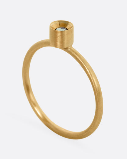 A yellow gold ring with a tourmaline, shown from the side standing up.