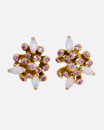 A pair of yellow gold starburst stud earrings with pink sapphires and opals, shown from the front.