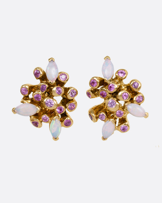 A pair of yellow gold starburst stud earrings with pink sapphires and opals, shown from the front.