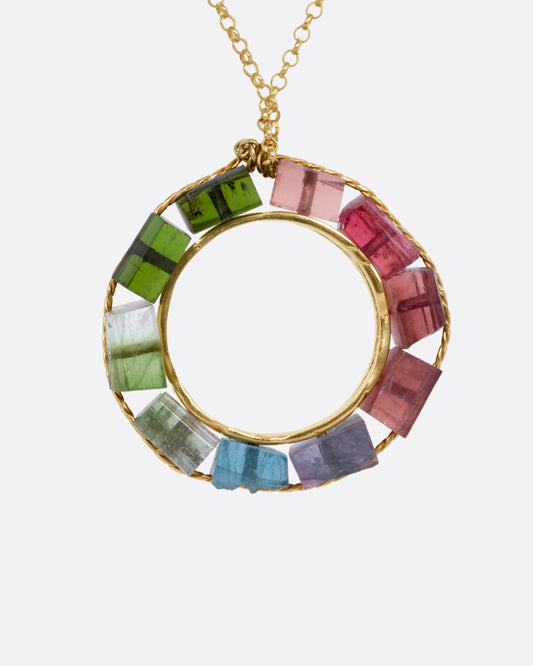 A yellow gold cable chain necklace with an open circular pendant featuring multicolored tourmalines. Shown from the front.