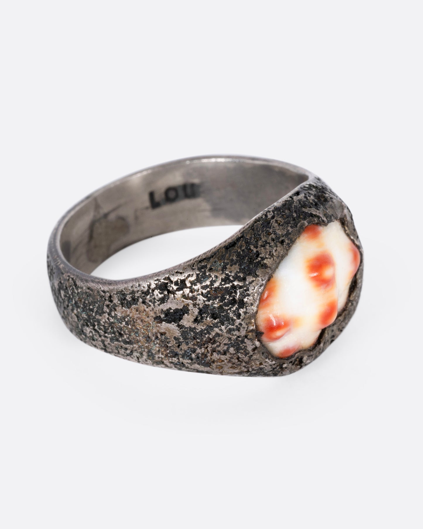A silver signet ring with a speckled shell, shown from the side.