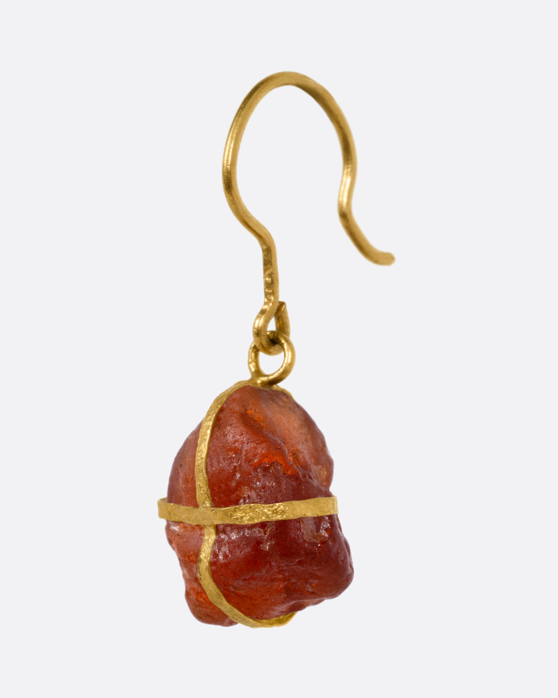 A yellow gold drop earring with a gold wrapped raw rubelite, shown from the side.