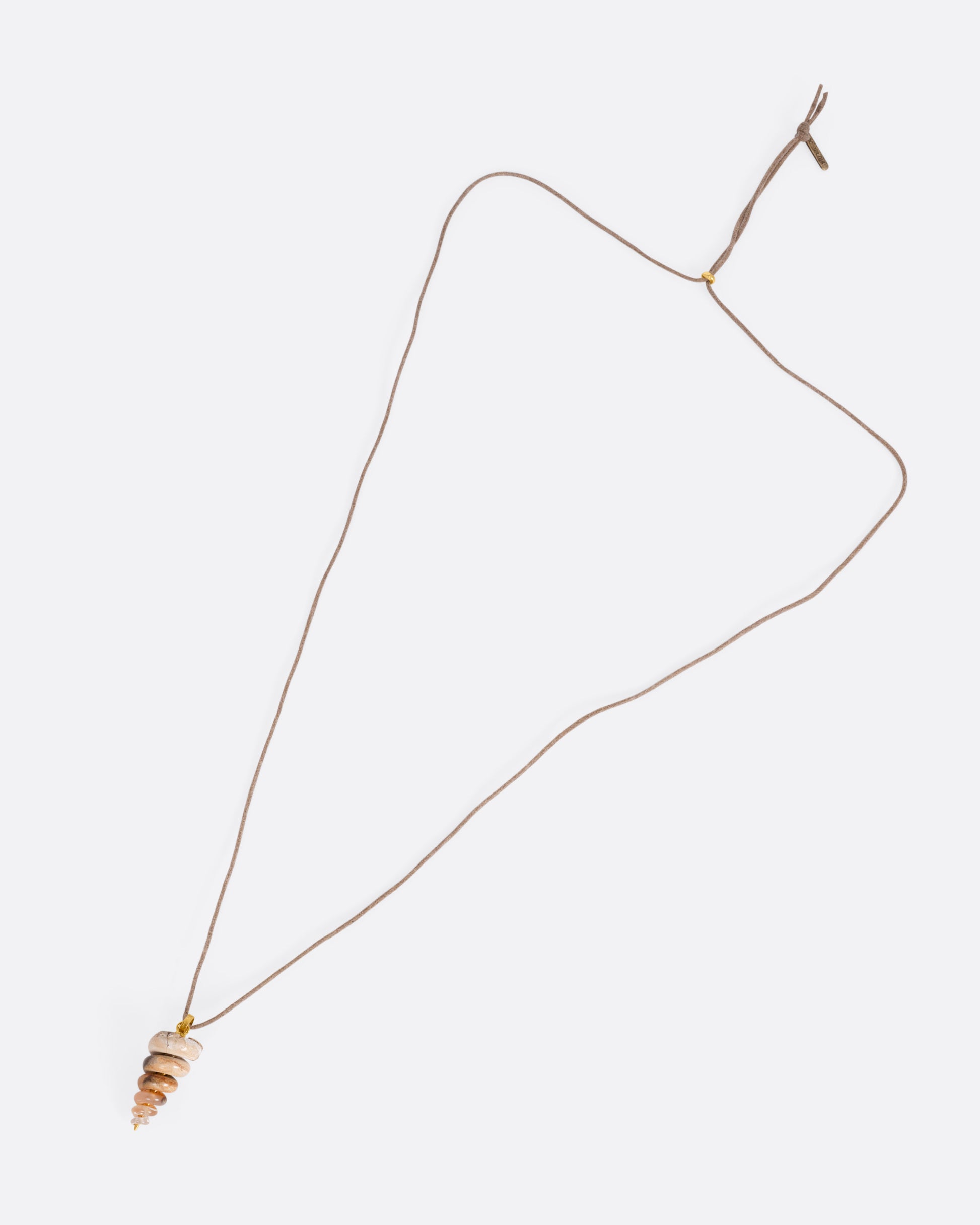 A yellow gold pendant with a  fossilized snail on a cord, shown from the front.