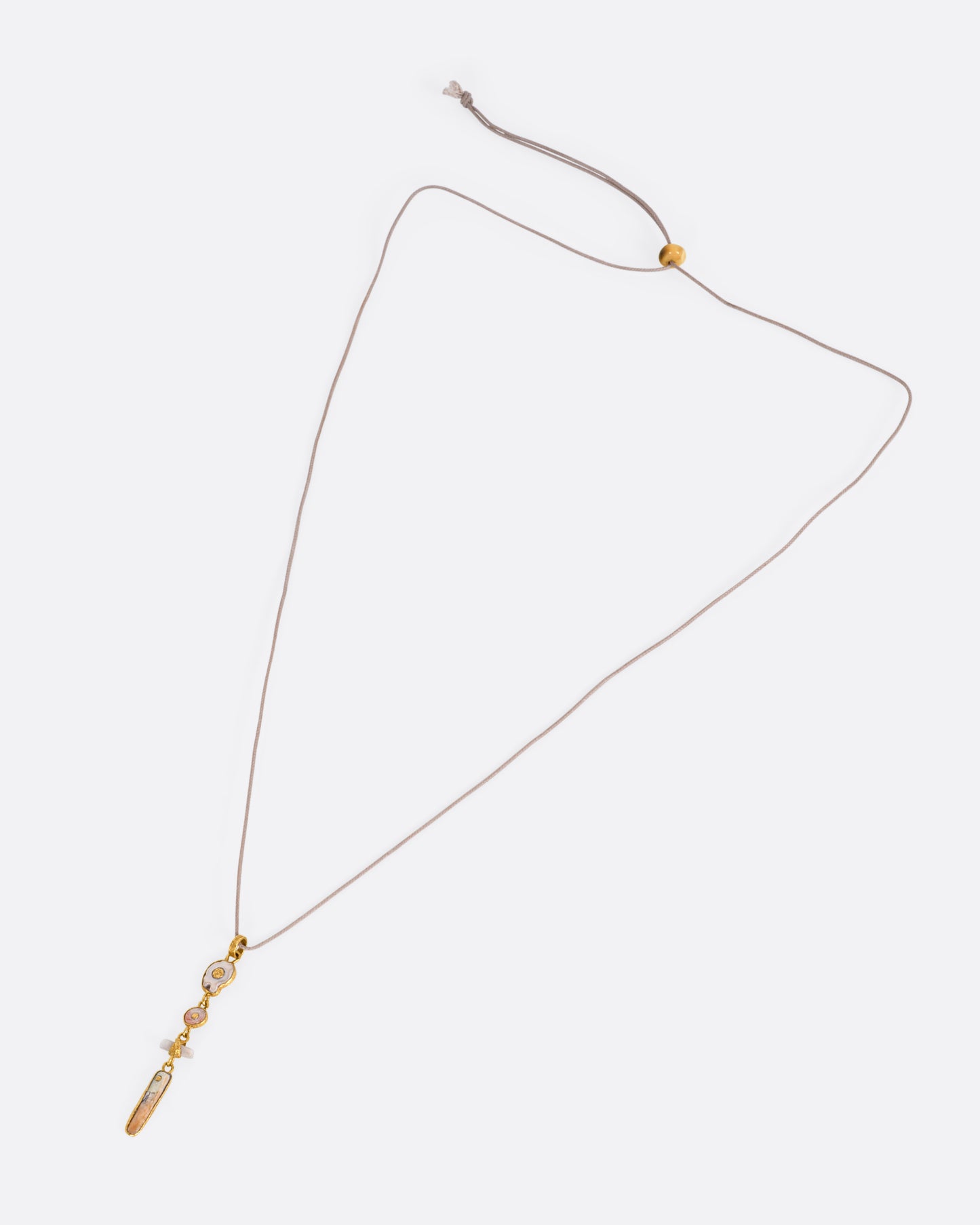 A yellow gold pendant with four gold wrapped pieces on a cord, shown from the front.